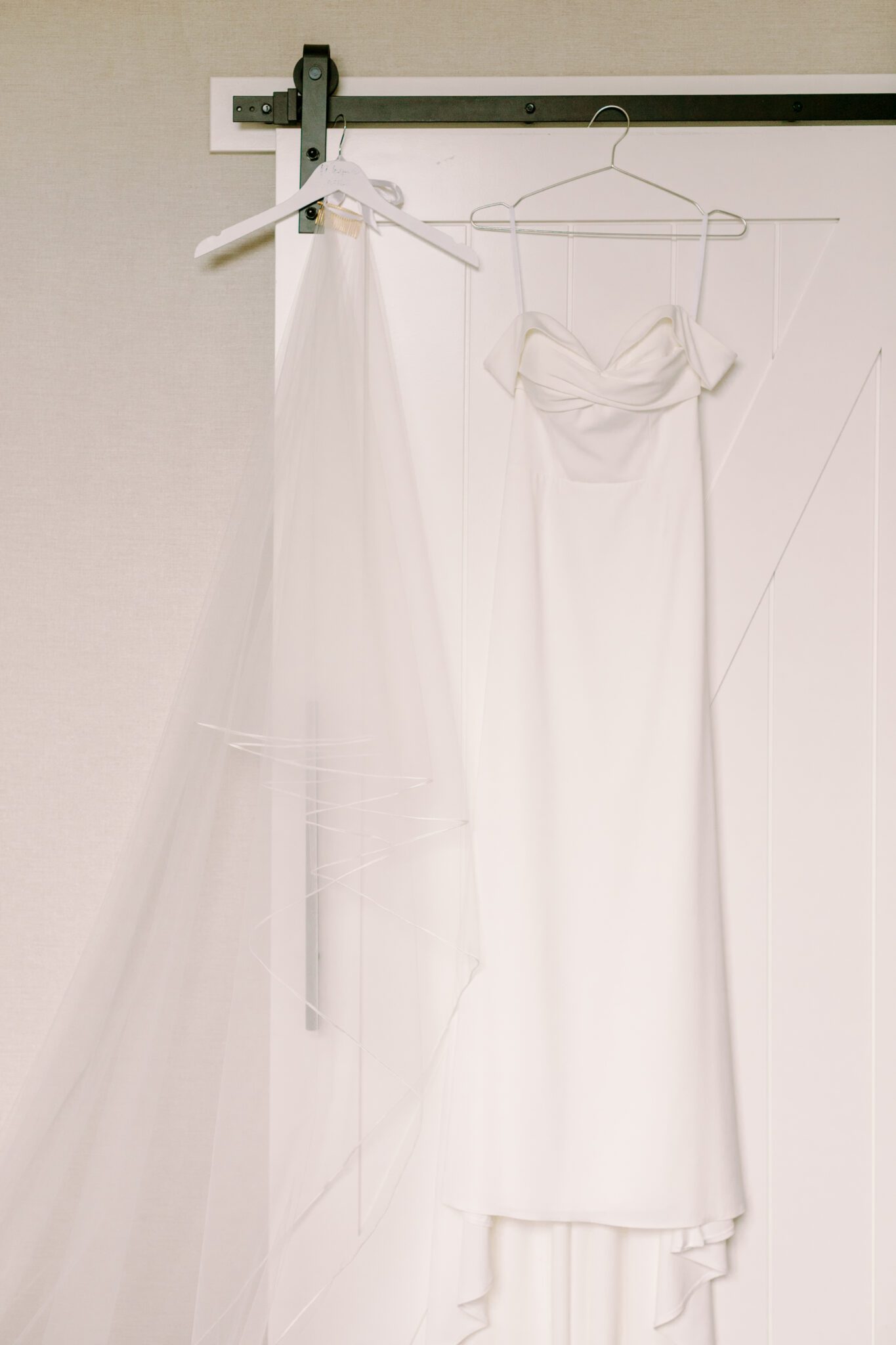 Brides getting ready details at The Malcolm Hotel. Wedding dress and veil hanging on sliding barn door.