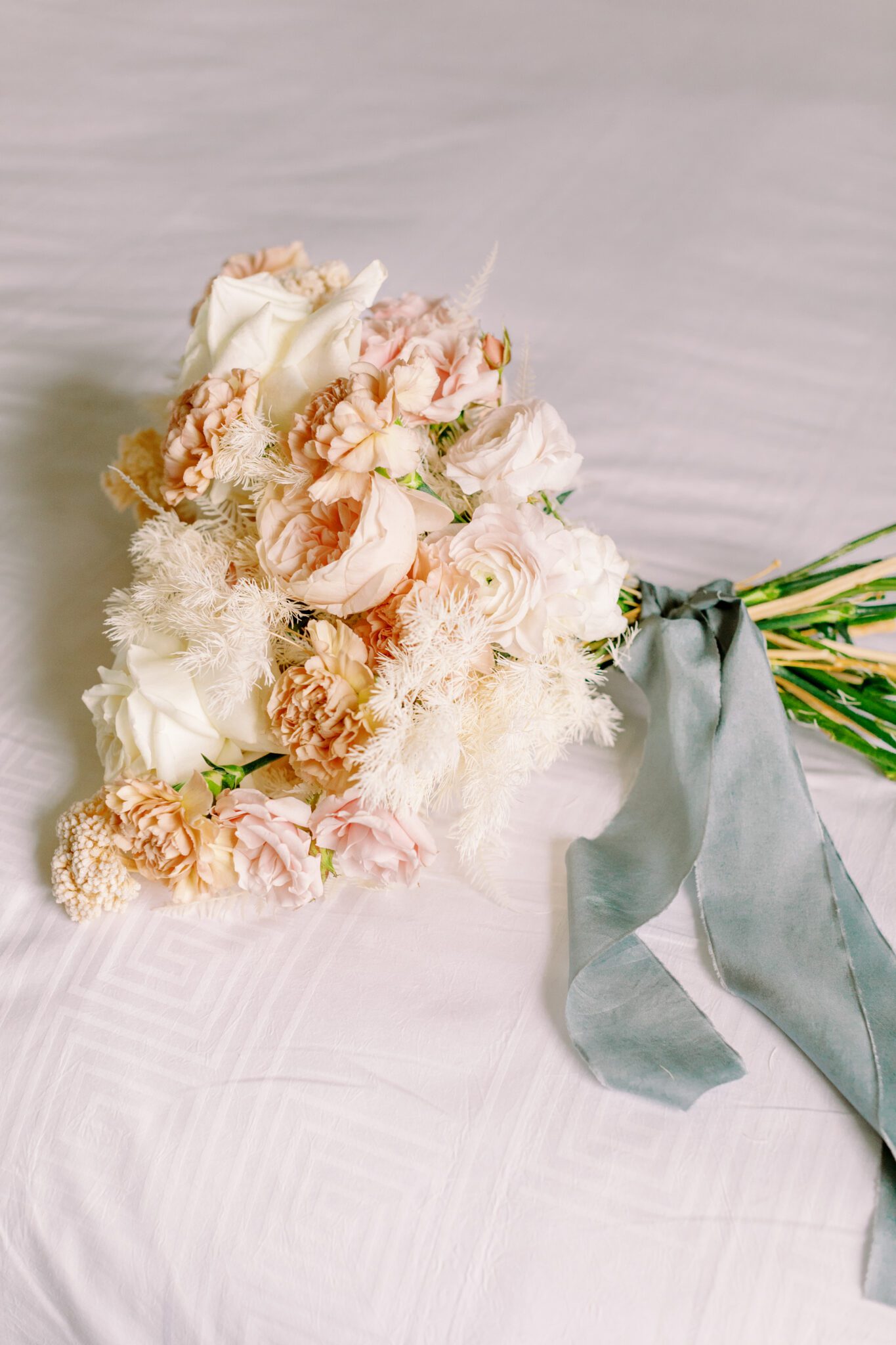 Brides getting ready details at The Malcolm Hotel. Bridal bouquet of pink, peach and white florals tied with a teal silk ribbon. 