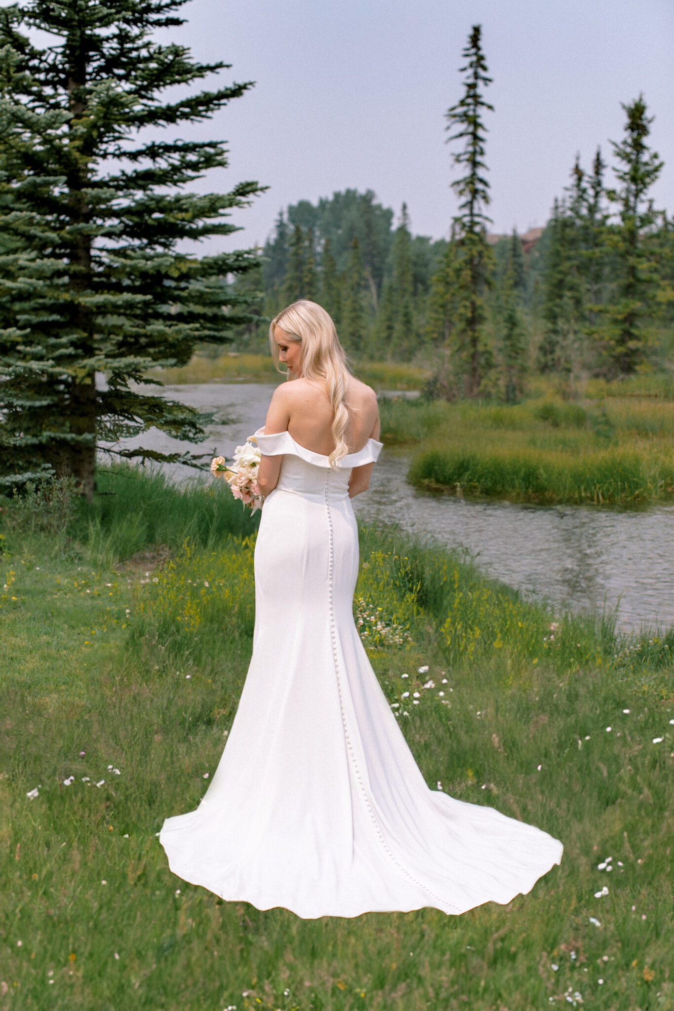 Bridal portrait in Canmore, Alberta. Bride wearing sleek, form-fitting wedding gown with off-the-shoulder sleeves.