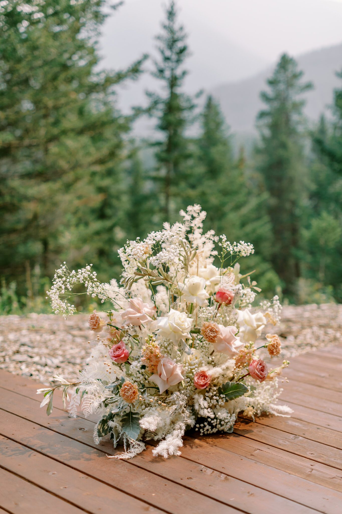 Wedding ceremony setup at Stewart Creek Golf Course in Canmore, Alberta. White, peach and pink florals. Mountain wedding ceremony. 