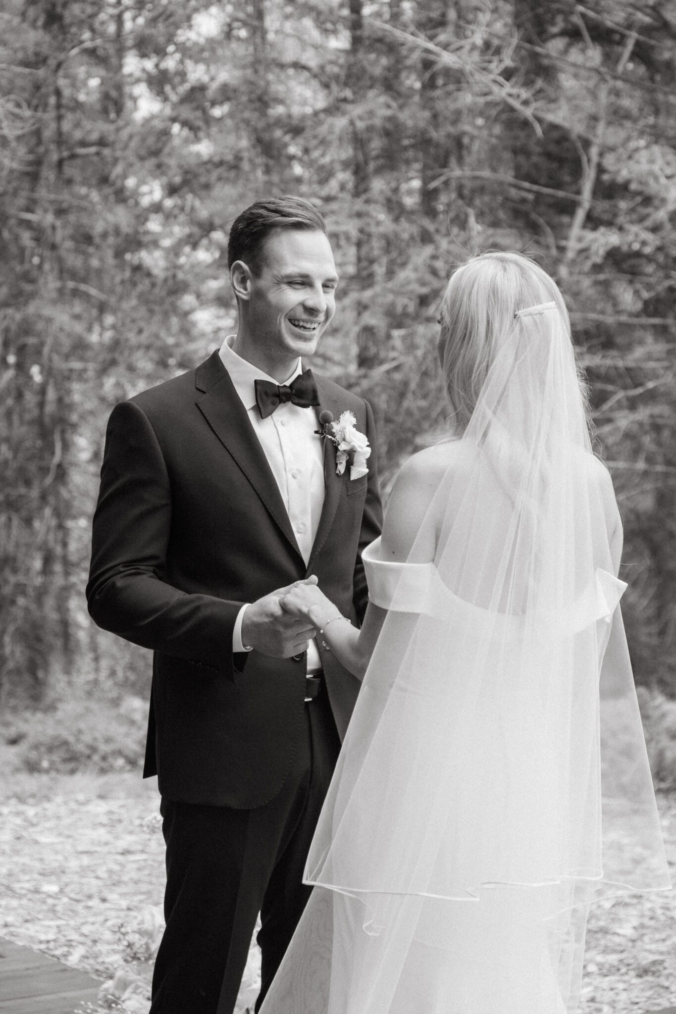 Bride and groom during wedding ceremony at Stewart Creek Golf Course in Canmore, Alberta. White, peach and pink florals. Mountain wedding ceremony. 