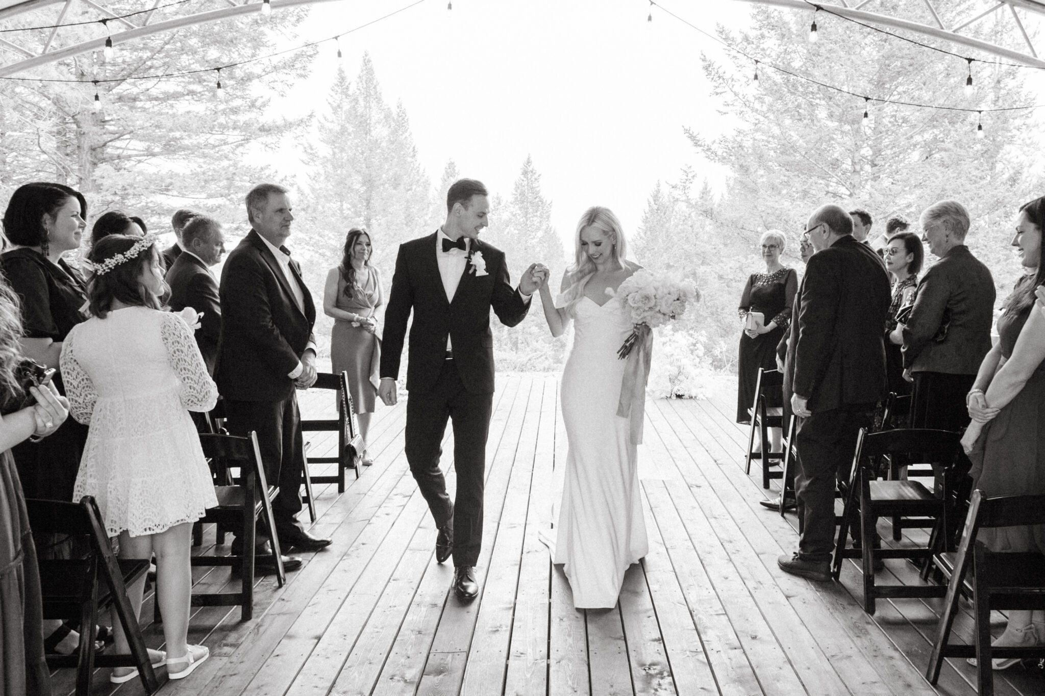 Bride and groom during wedding ceremony at Stewart Creek Golf Course in Canmore, Alberta. White, peach and pink florals. Mountain wedding ceremony. 