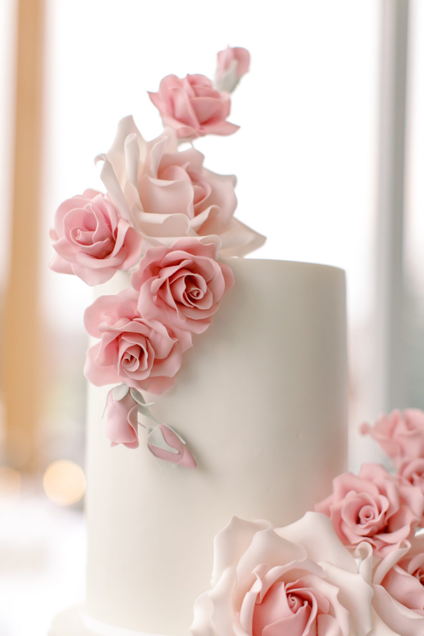 Beautiful 2-tiered white wedding cake with pink sugar roses created by Yvonne's Delightful Cakes.