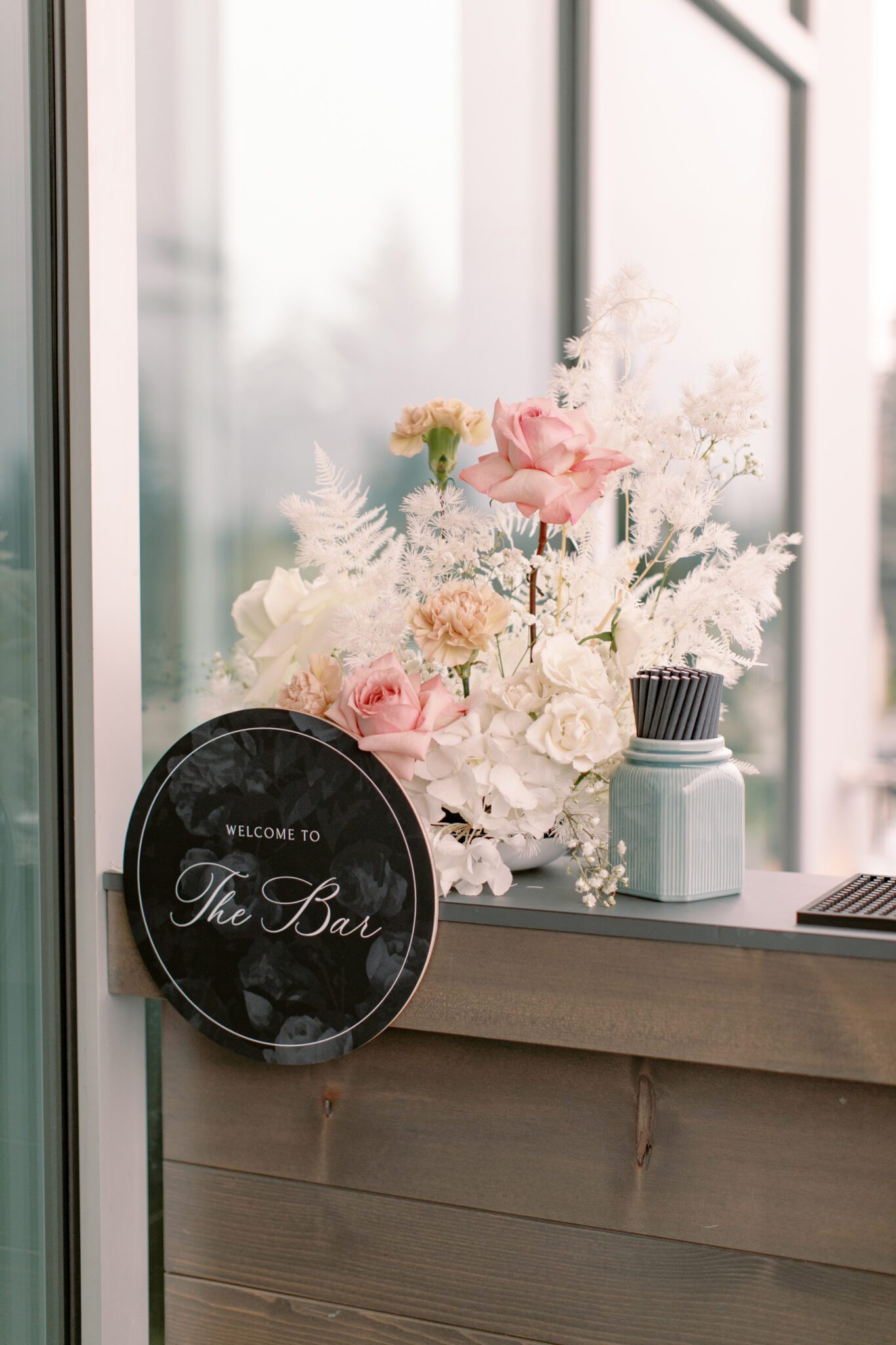 Wedding reception bar  signage at The Sensory in Canmore, Alberta. Black and white wedding signs surrounded by pink and white florals.
