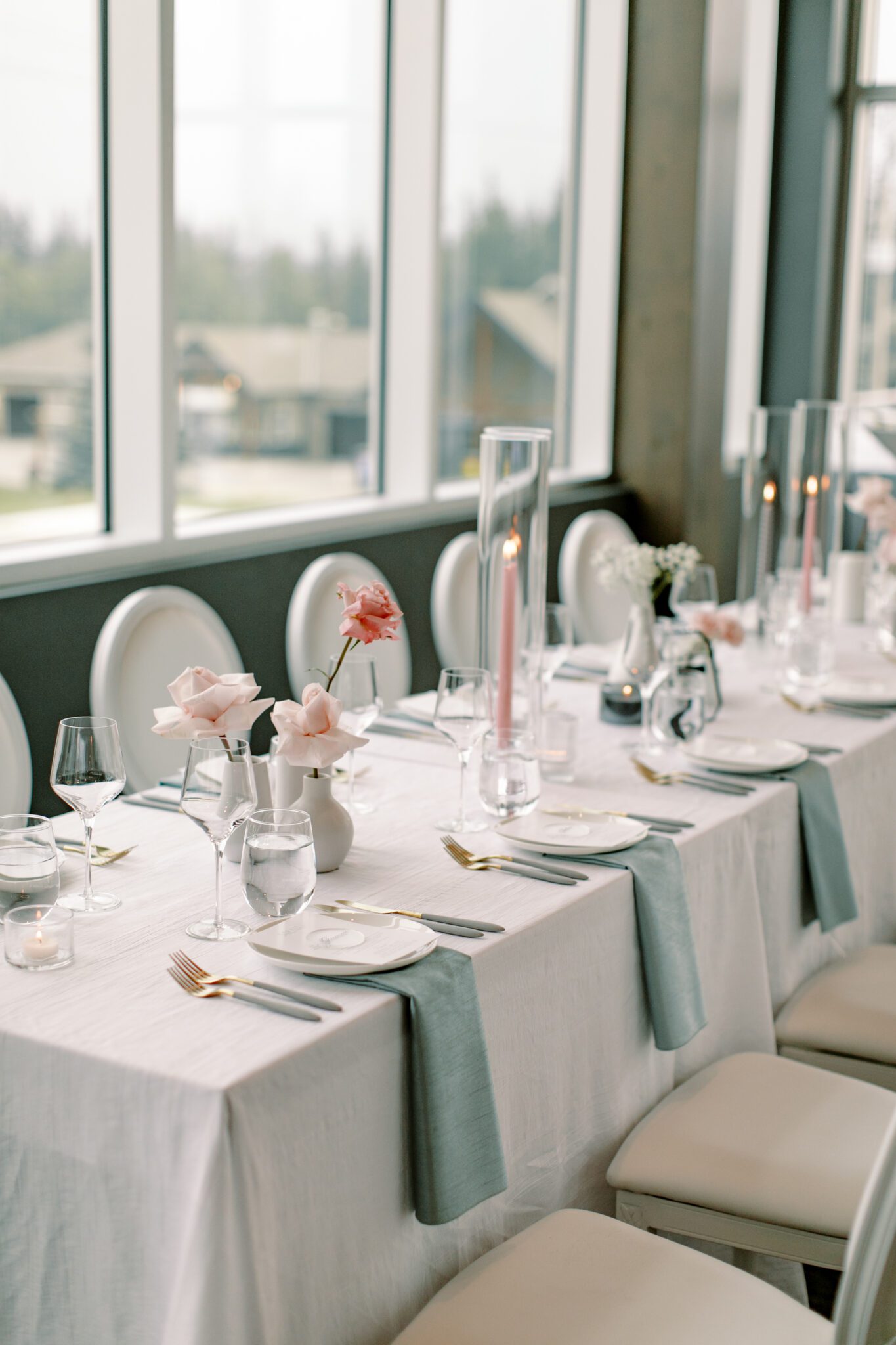 Modern and chic wedding reception at The Sensory in Canmore, Alberta.  Long tables with white linens, blue napkins, and pink floral centrepieces
