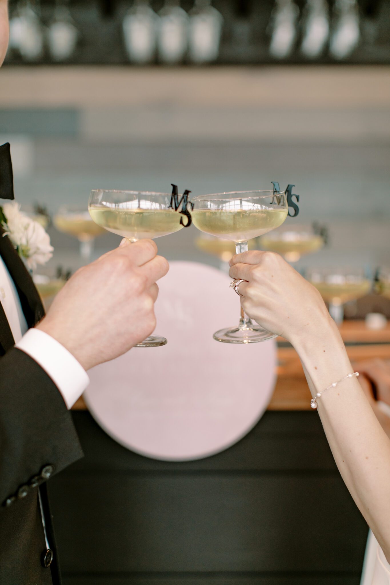 Bride and groom cheers champagne glasses with custom monogram glass toppers. 