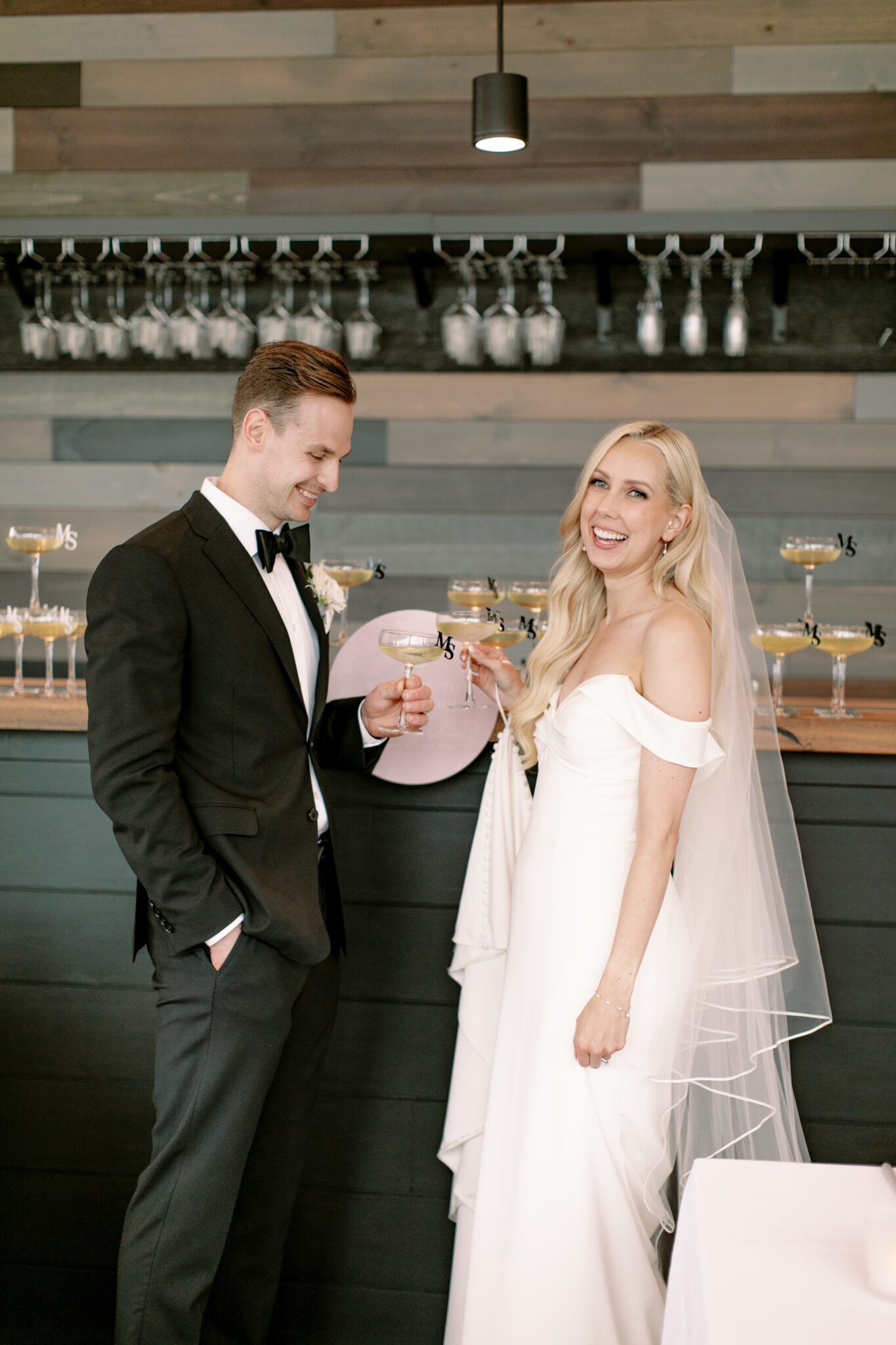 Bride and groom cheers champagne glasses with custom monogram glass toppers. 