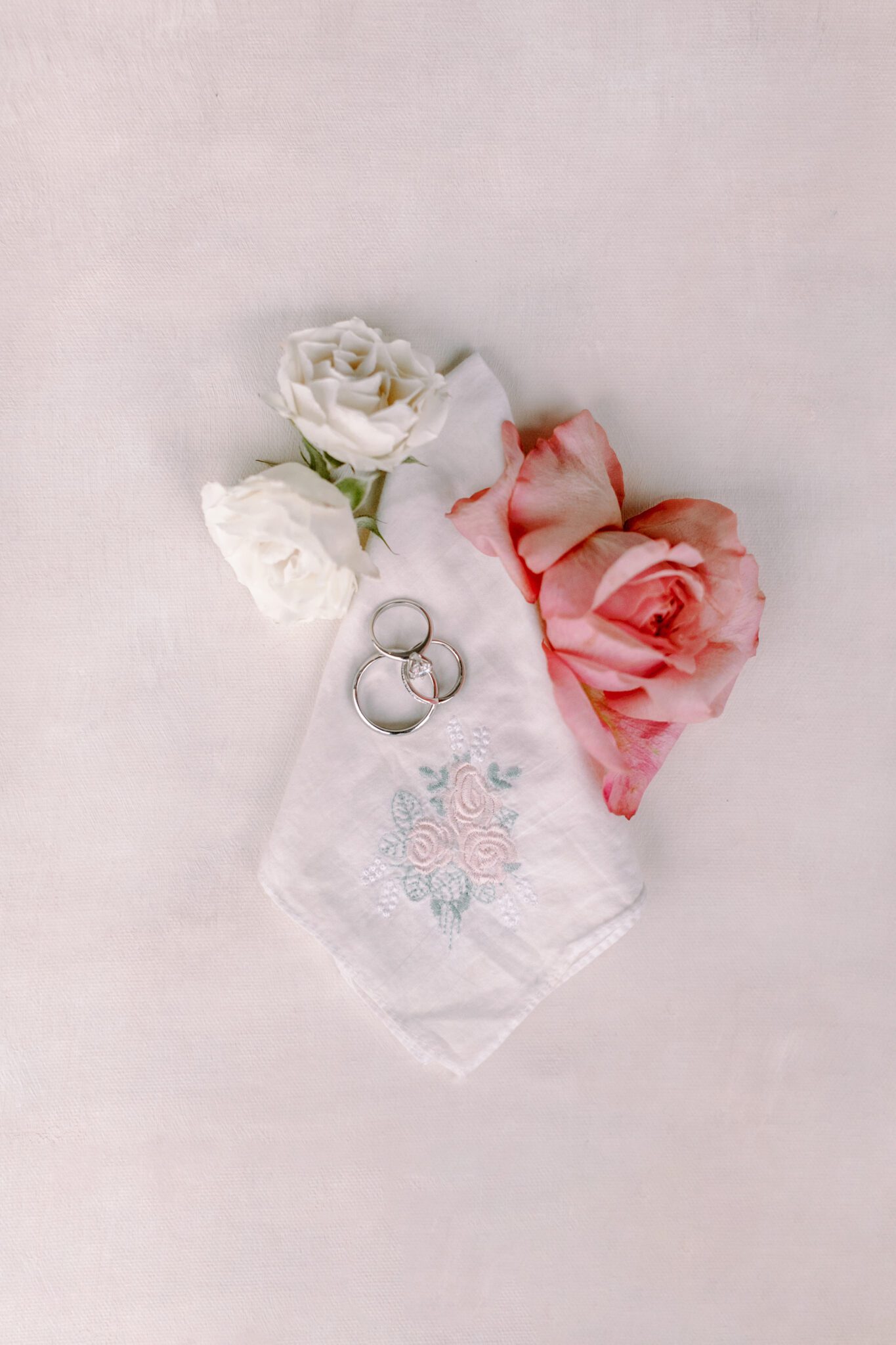 Wedding detail photo inspiration. Handkerchief, wedding rings and white and pink roses. 