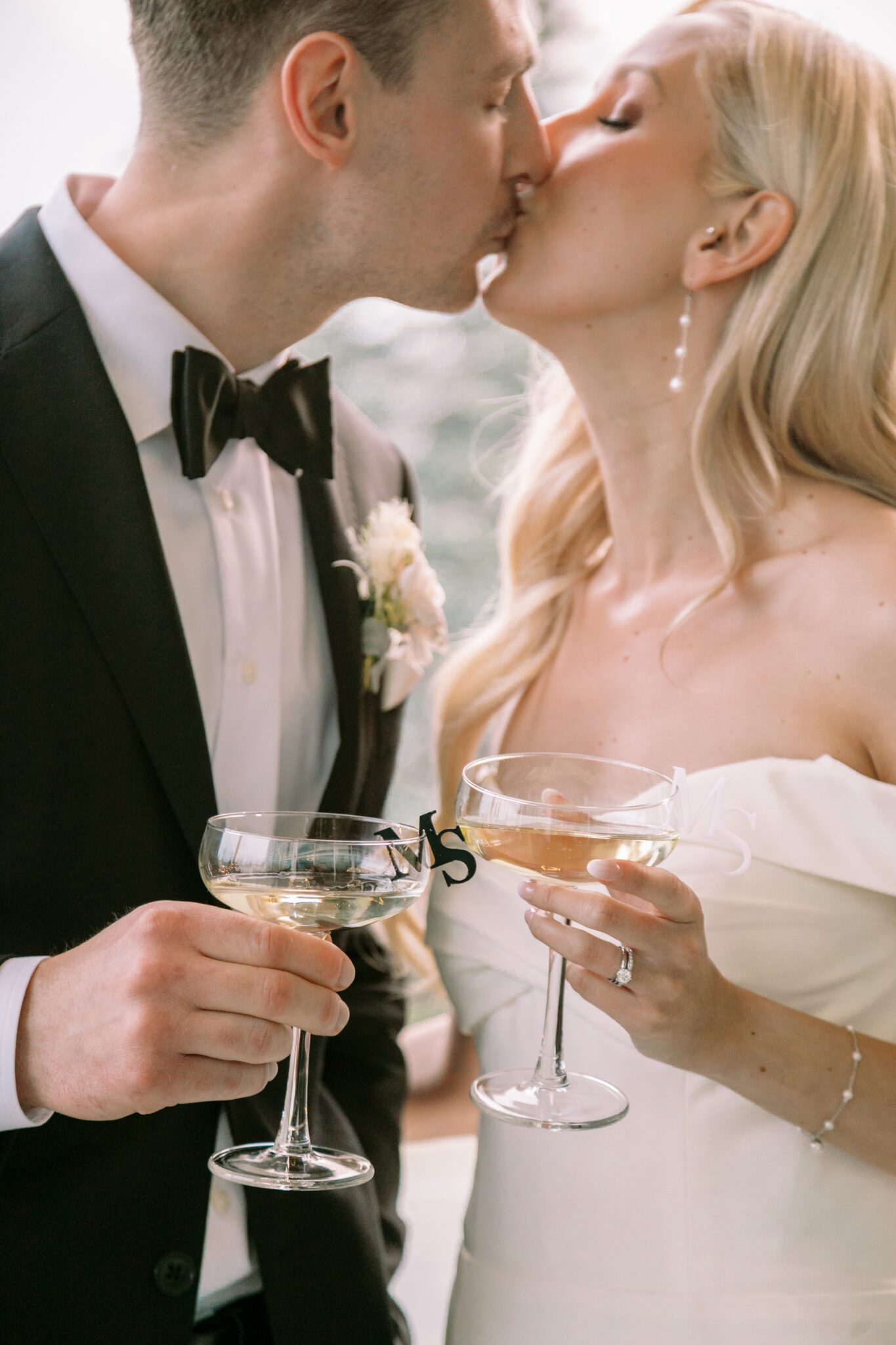 Bride and groom cheers champagne glasses with custom monogram glass toppers. 