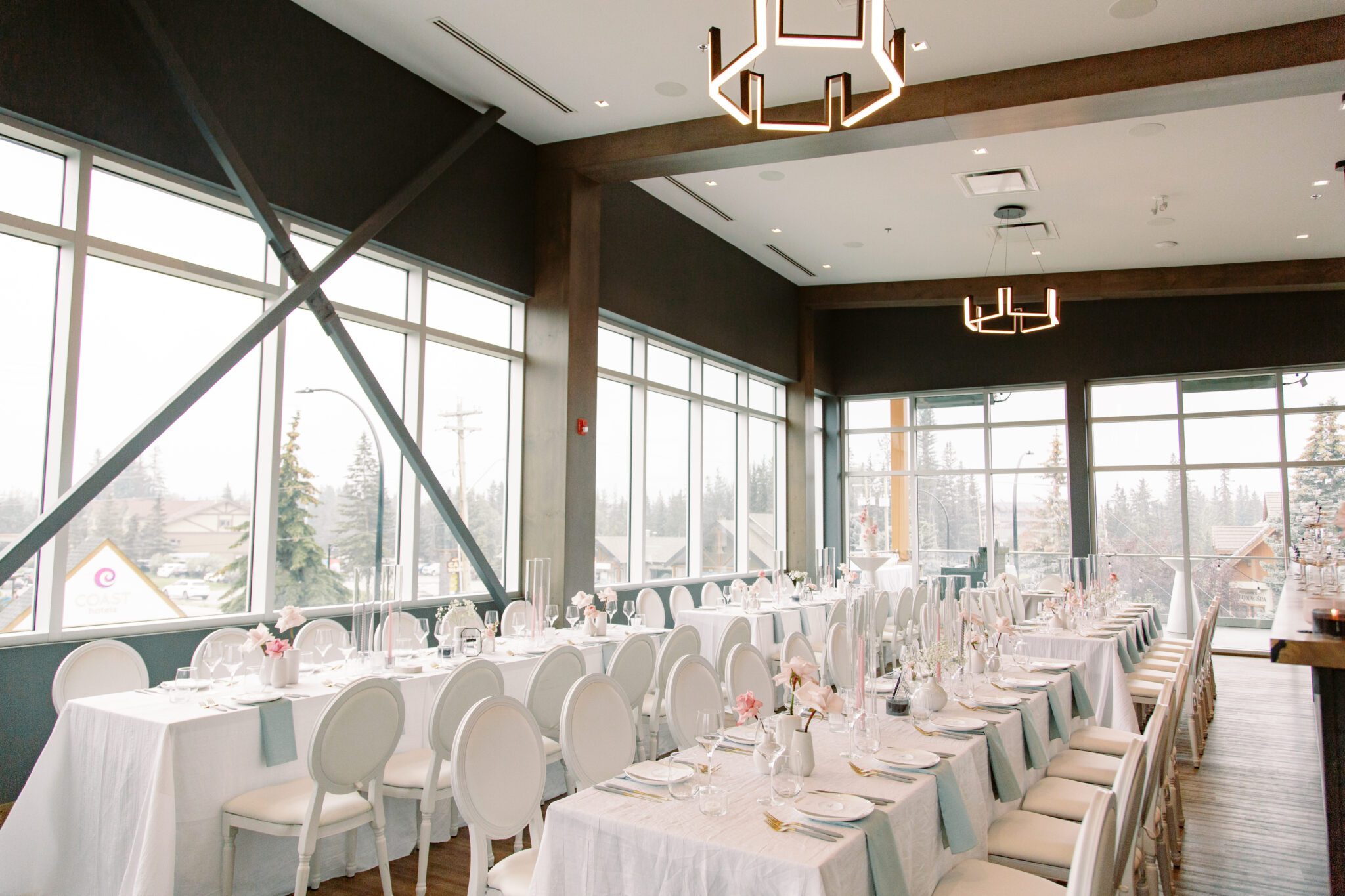 Modern and chic wedding reception at The Sensory in Canmore, Alberta.  Long tables with white linens, blue napkins, pink floral centrepieces