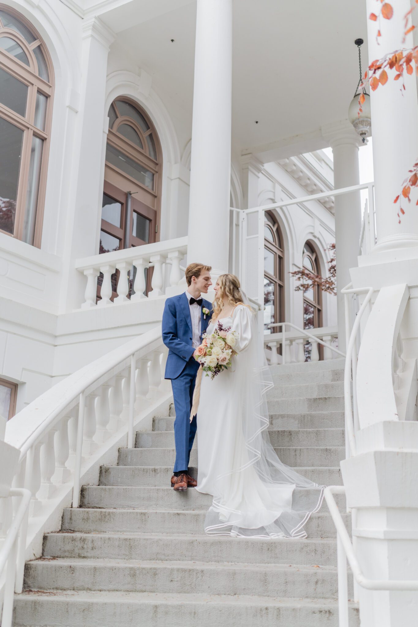 Bride and groom embracing at a timeless elegant wedding at Chilliwack Museum. Featuring the museum's classical architecture featuring pillars, arch windows and a grand staircase.