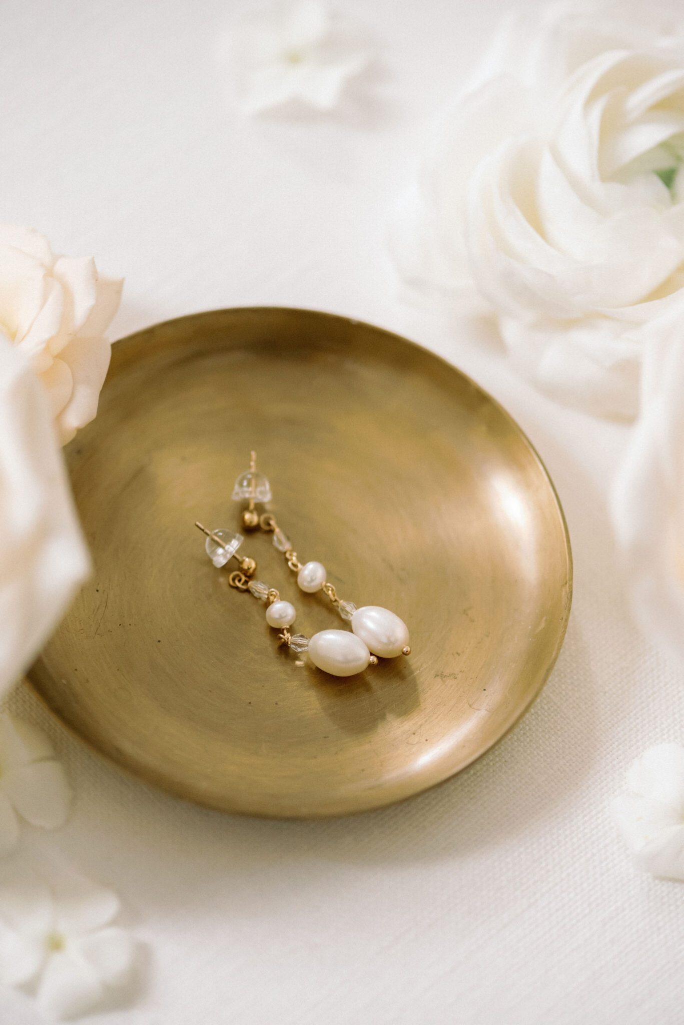 Gold and pearl drop bridal earrings in gold jewelry dish. 