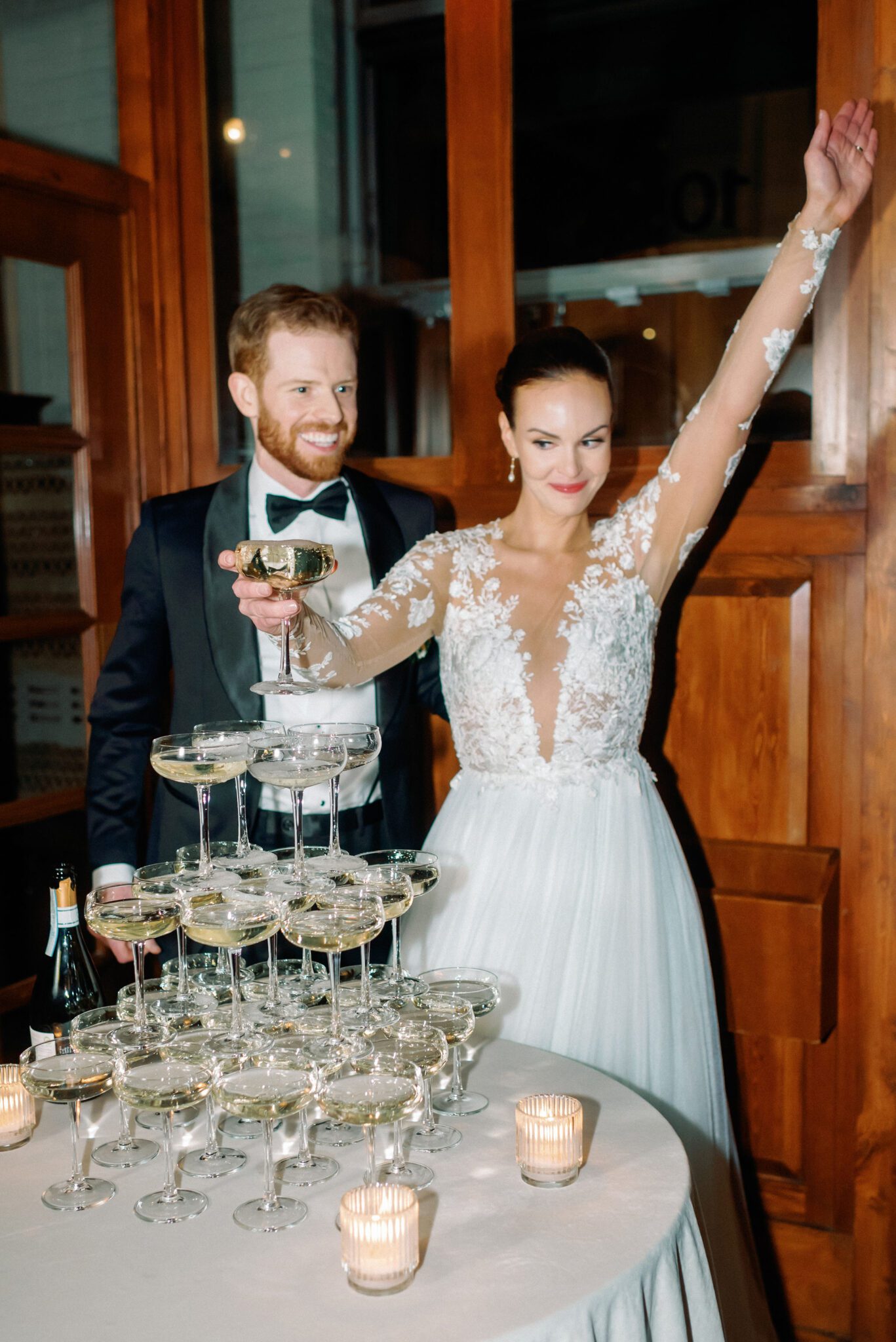 Bride and groom pose in front of champagne tower during Bonterra Trattoria wedding reception in Calgary, Alberta. 