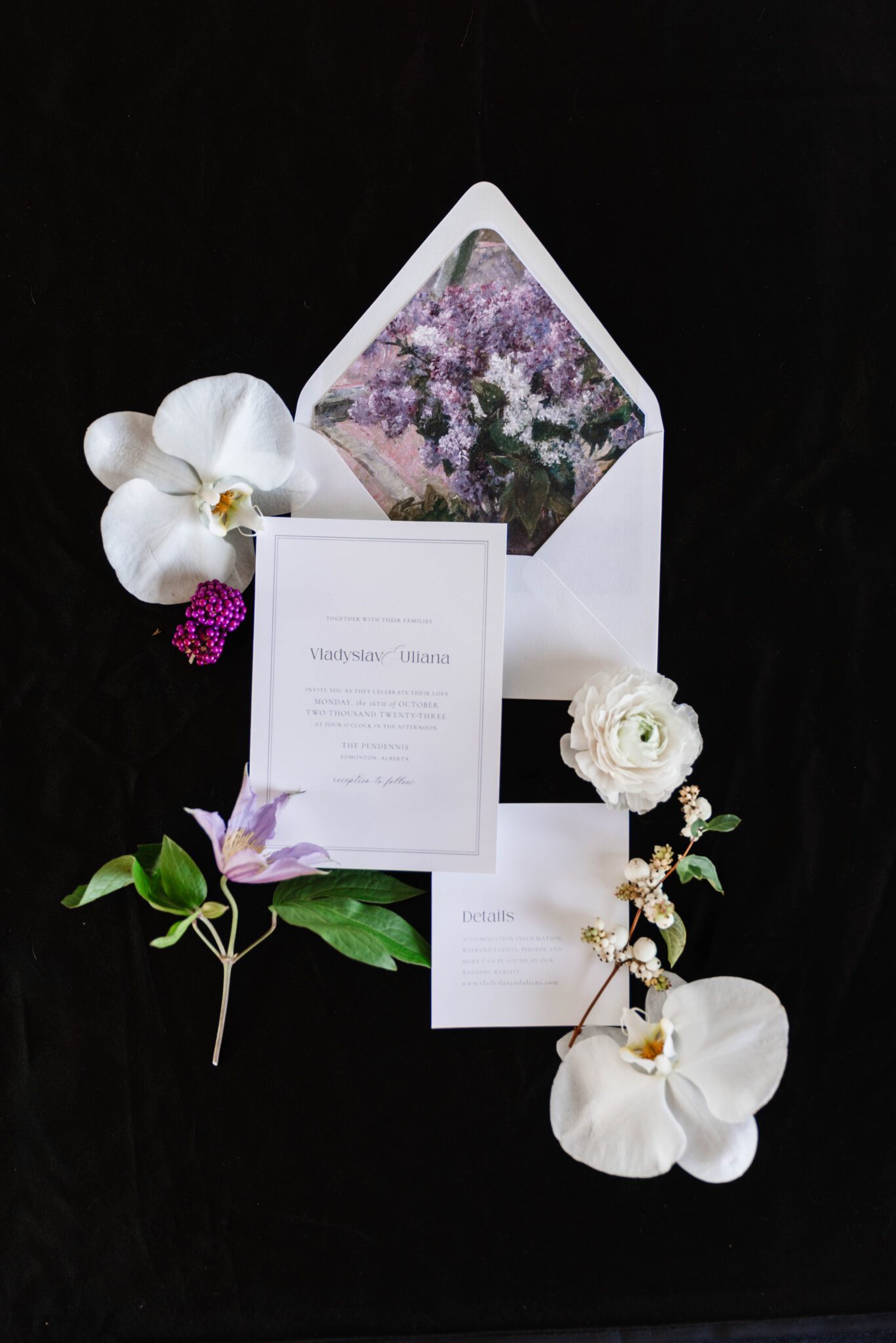 Purple garden wedding inspiration. Floral invitation paper suite flat lay surrounded by white orchids and purple florals.