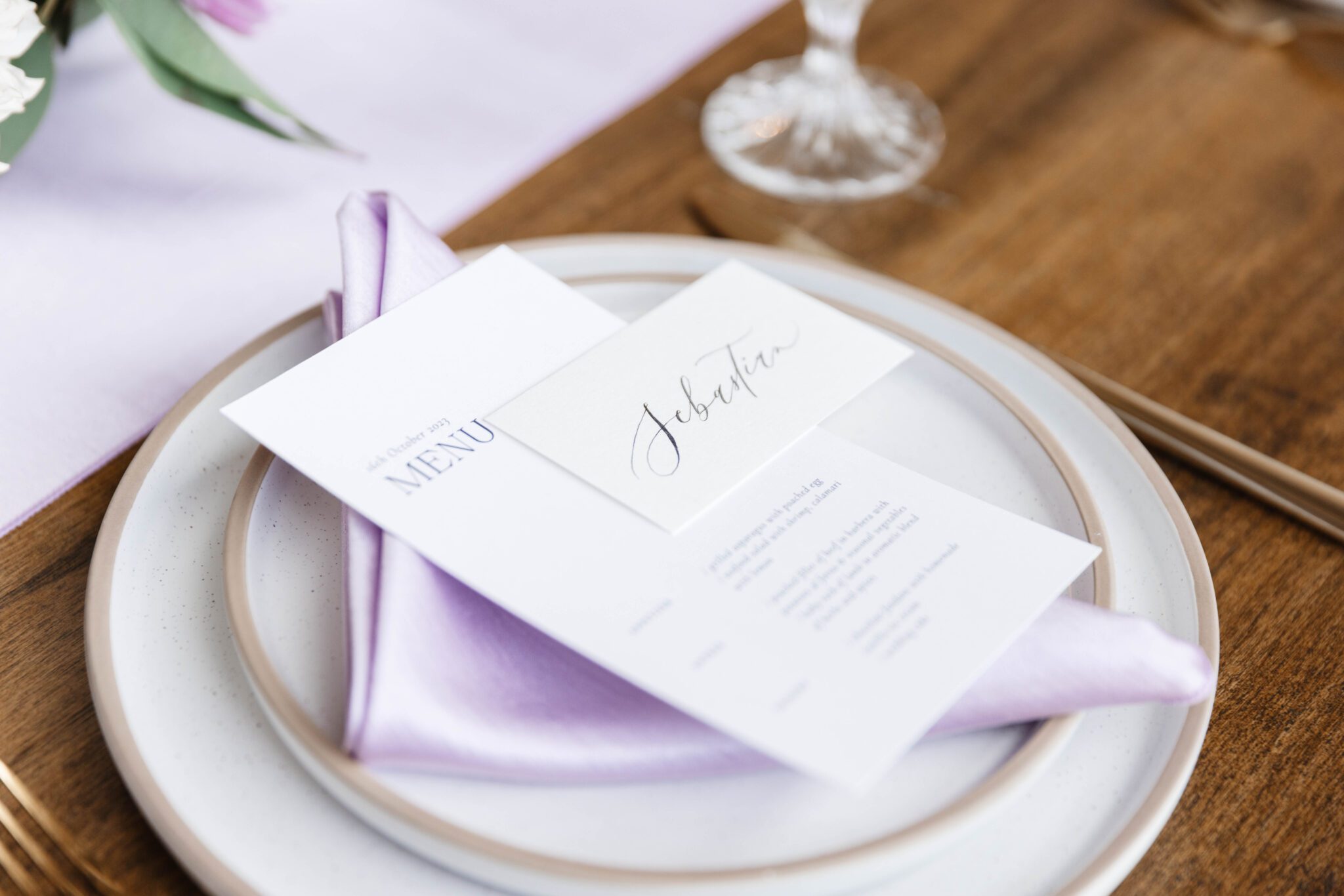 Reception tablescape at The Pendennis featuring lush purple garden party inspired wedding florals, purple table runner, floral candle holder. Custom calligraphy place holders by Written by Winh.