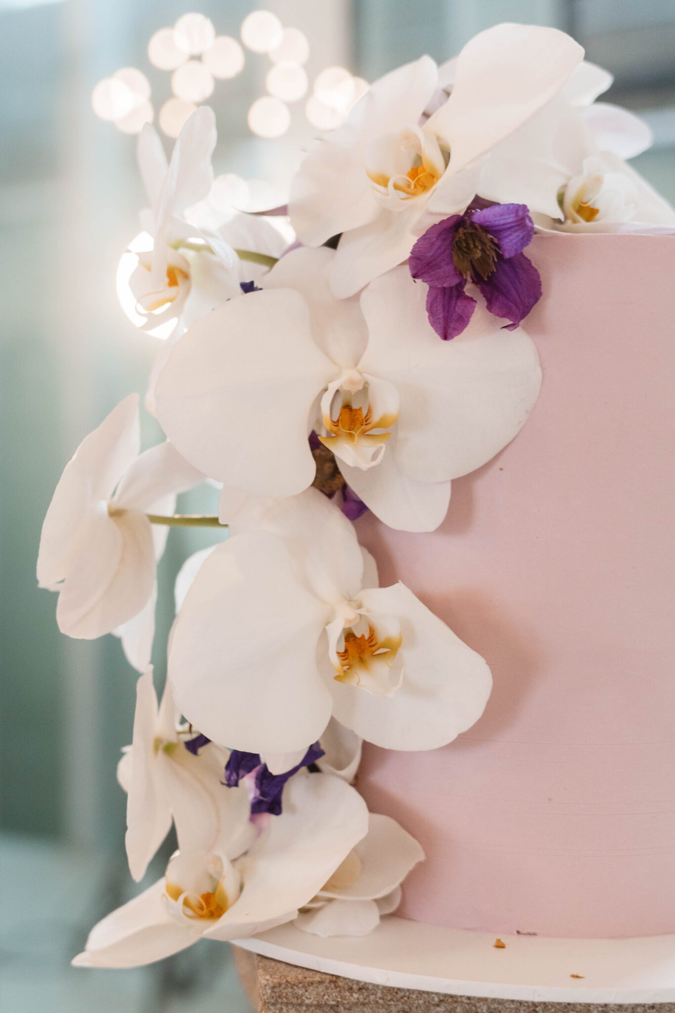 Elegant one-tiered pink wedding cake topped with cascading white orchids. 