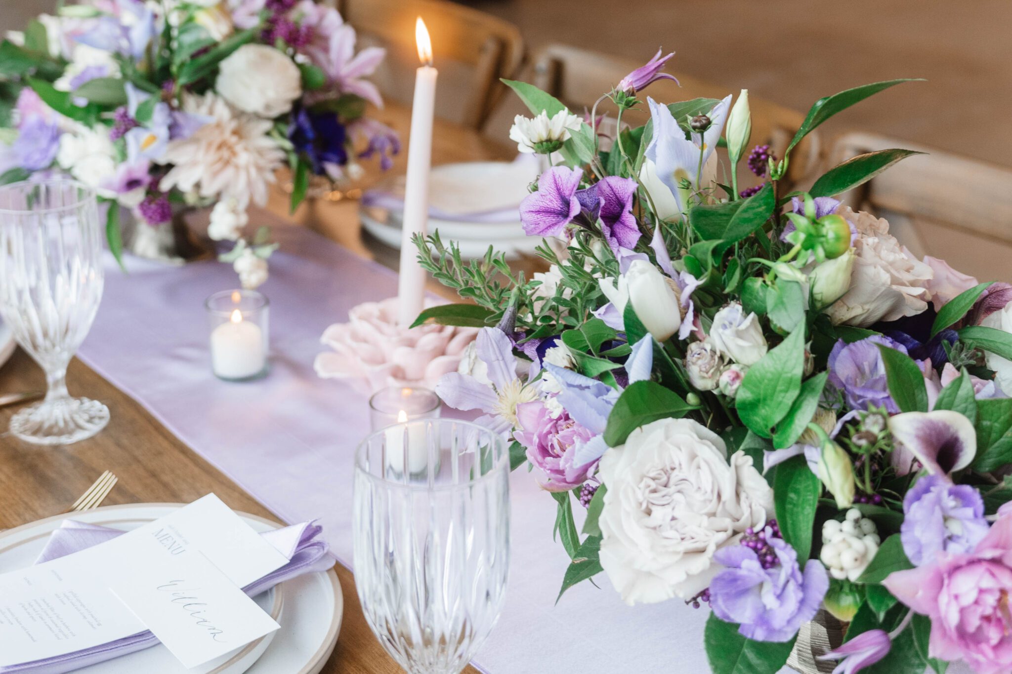 Reception tablescape at The Pendennis featuring lush purple garden party inspired wedding florals, purple table runner, floral candle holder.