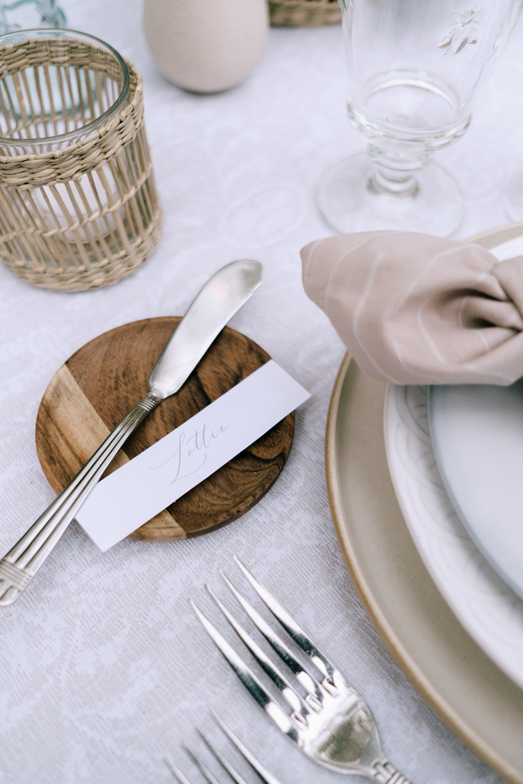 Warm and inviting wedding table with wood-toned butter plates, organic floral bud vases, and rustic charm.