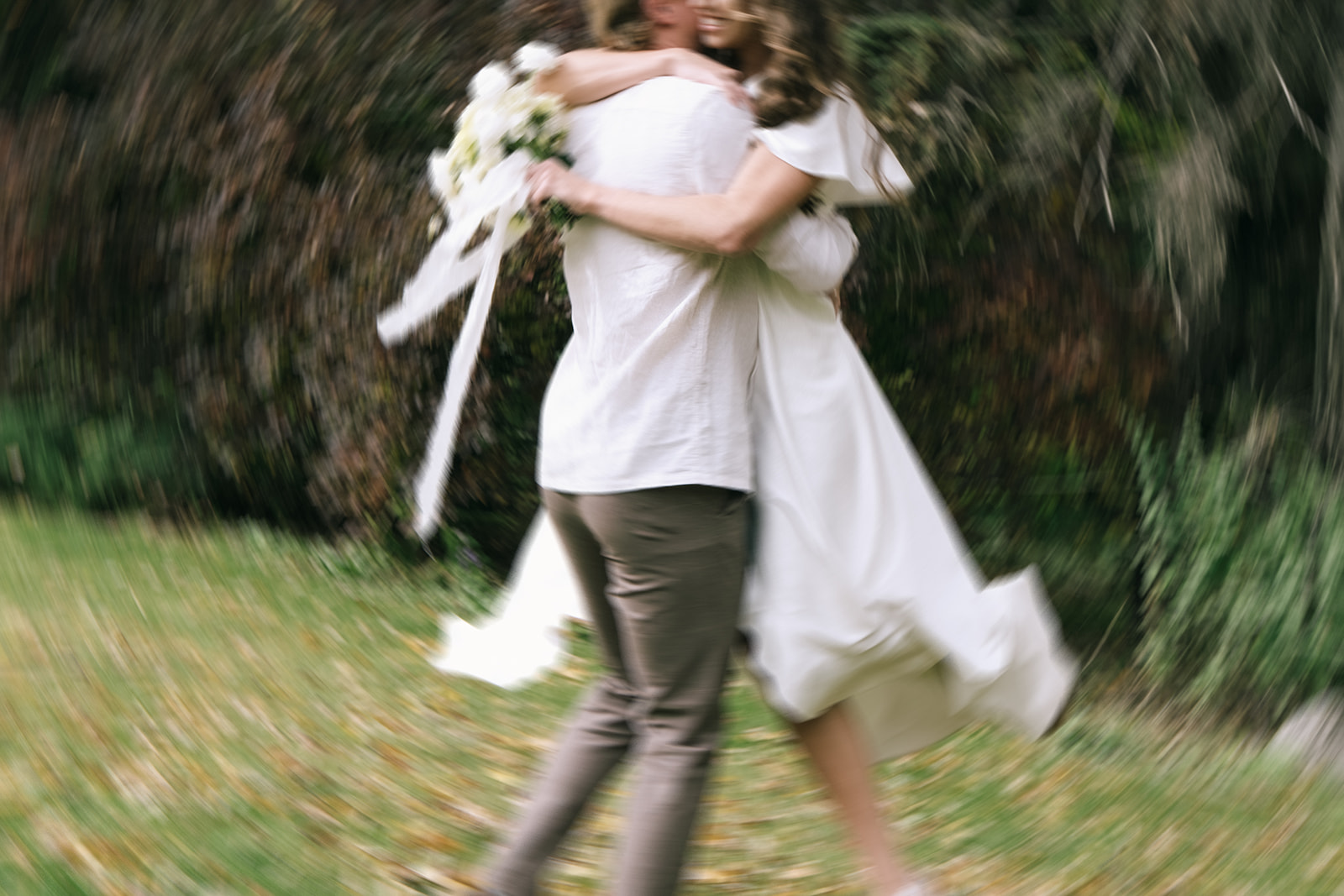 Groom spinning the bride in a relaxed dance, both wearing casual linen outfits perfect for a breezy summer wedding day. Backyard wedding ideas and inspiration.