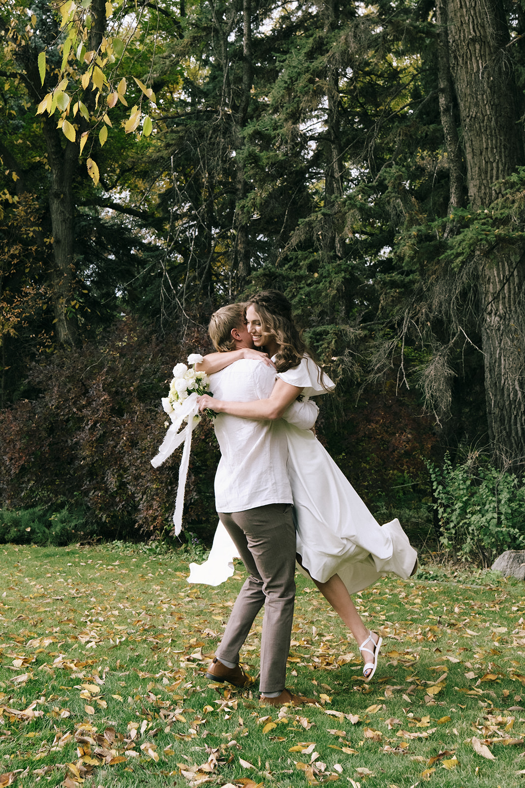 Groom spinning the bride in a relaxed dance, both wearing casual linen outfits perfect for a breezy summer wedding day. Cottage core summer wedding inspiration.