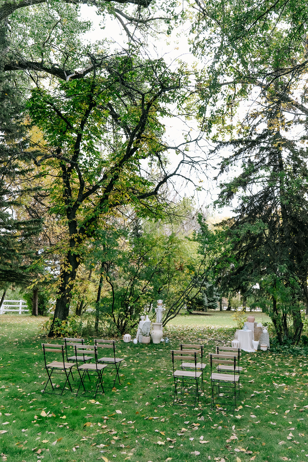 Cottage core wedding ceremony setup with delicate wildflowers and vintage wooden chairs in a lush garden setting at The Norland Historic Estate in Southern Alberta.