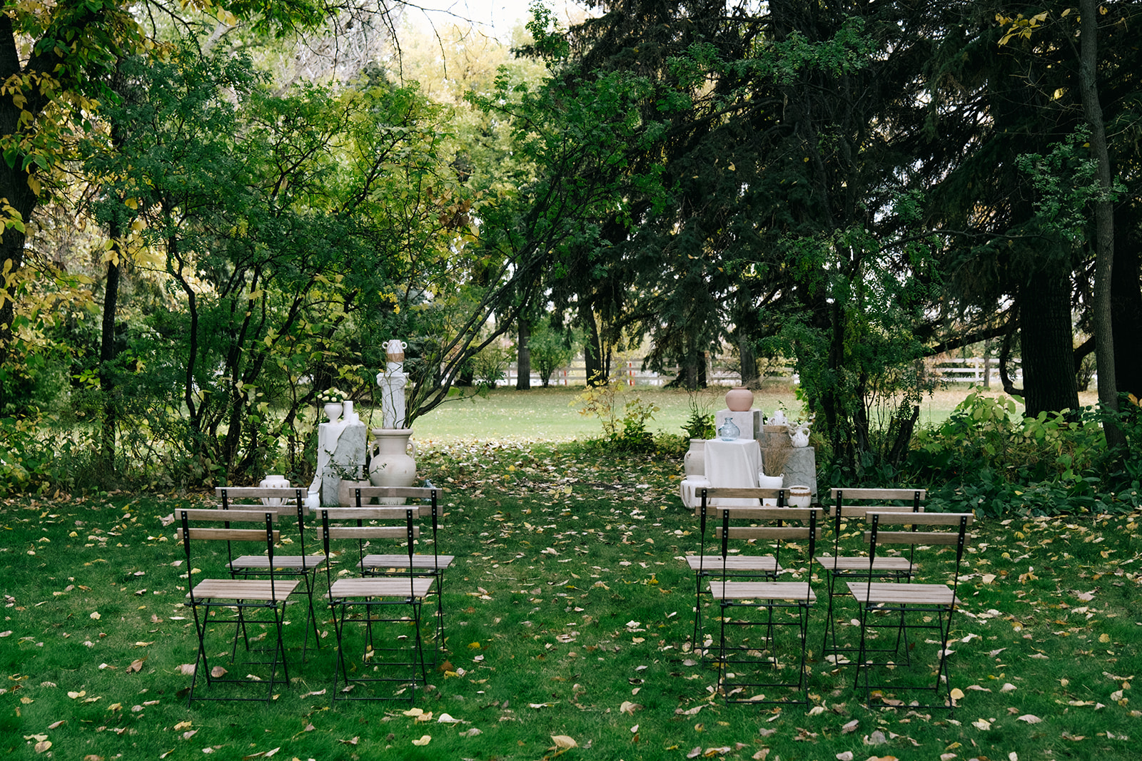 Cottage core wedding ceremony setup with delicate wildflowers and vintage wooden chairs in a lush garden setting at The Norland Historic Estate in Southern Alberta.
