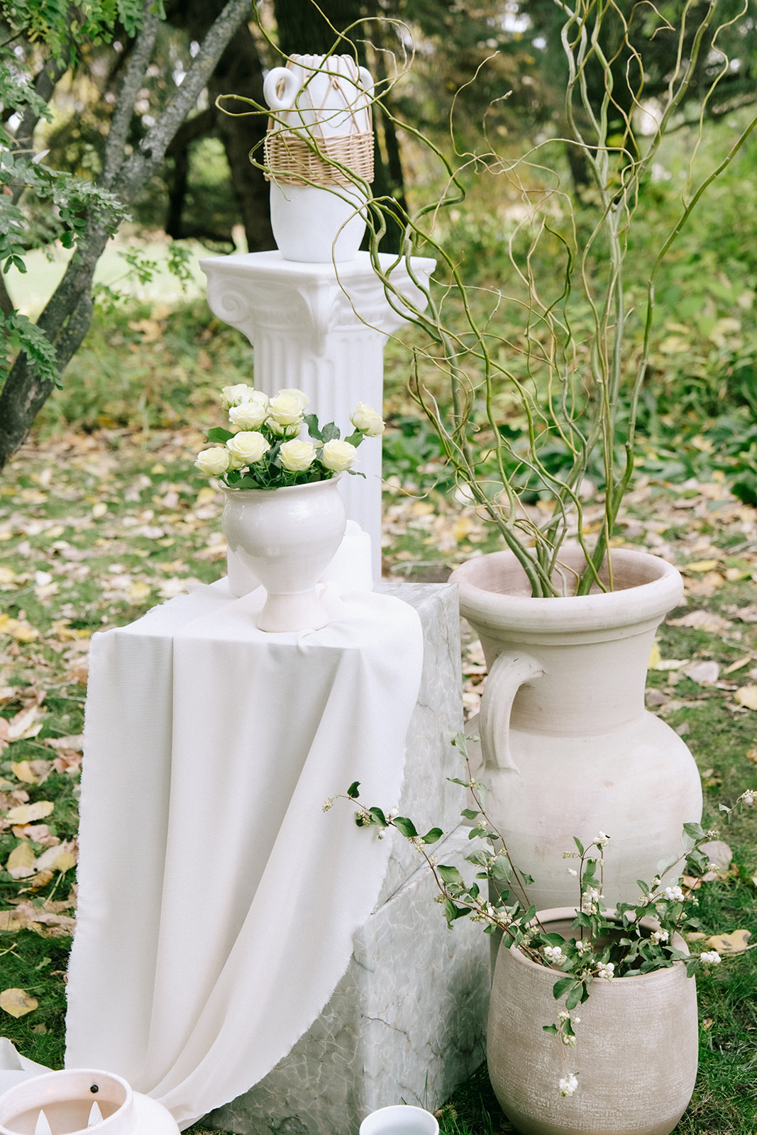 Pedestal stand ceremony arch design layered with flowy fabric, organic neutral vases with florals and candles. Cottage core inspired wedding aesthetic. 