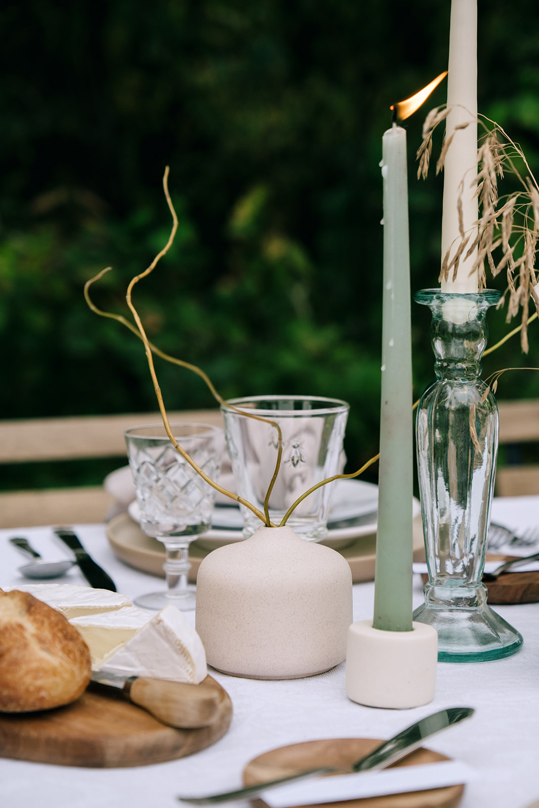 Cottage core wedding table with a subtle sheer patterned tablecloth, mist-colored taper candles, and organic floral centerpieces.