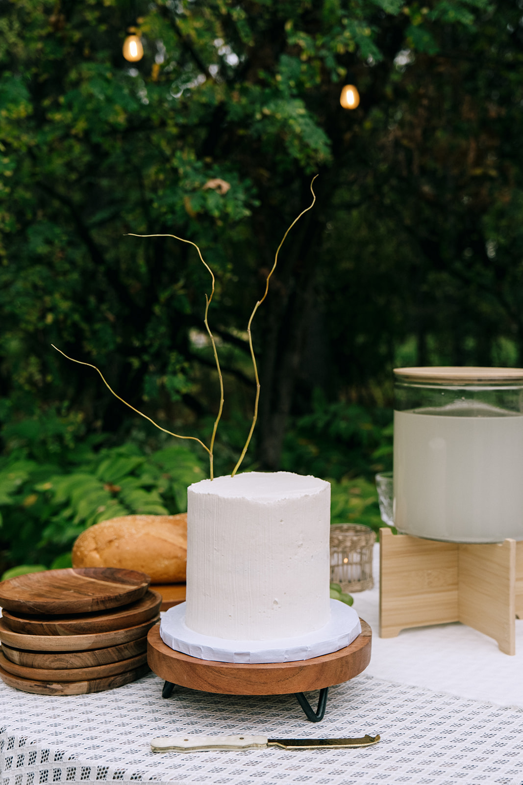 Charming serve-yourself drink station with prosecco, vintage glassware, and a seating chart display. Simple white one-tiered wedding cake.