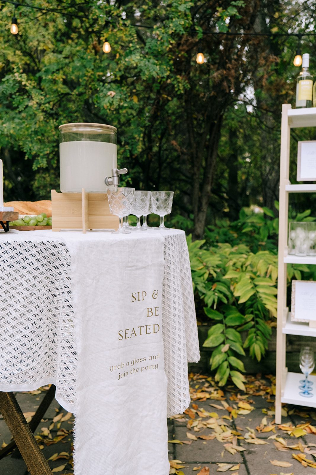 Charming serve-yourself drink station with prosecco, vintage glassware, and a seating chart display.