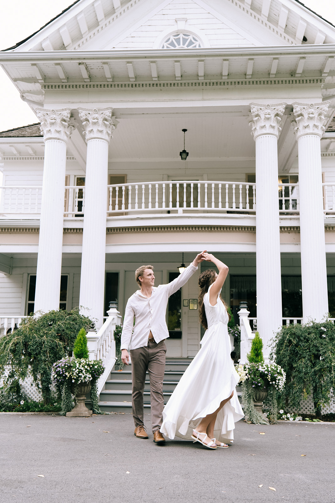 Couple dancing joyfully under the sun, embodying the relaxed and casual vibe of a laid-back summer wedding. Groom spinning the bride in a relaxed dance, both wearing casual linen outfits perfect for a breezy summer wedding day.