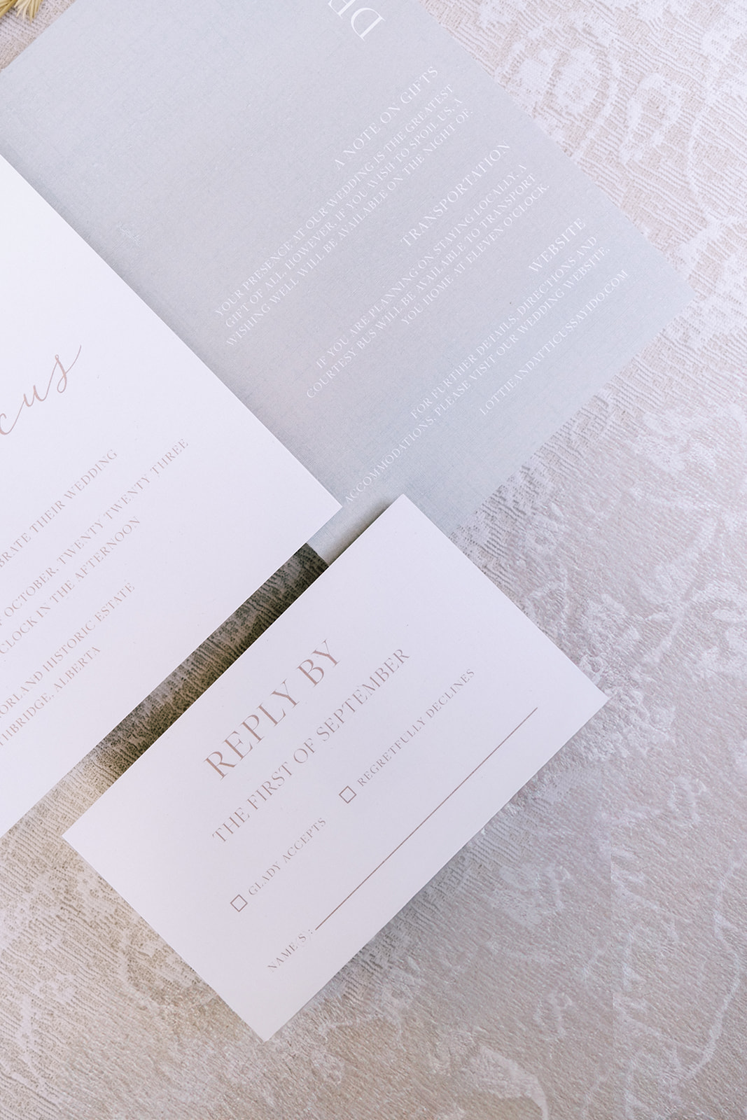 Close-up of pale yellow and dusty blue wedding stationery on a soft linen and lace tablecloth, embracing the cottage core aesthetic.