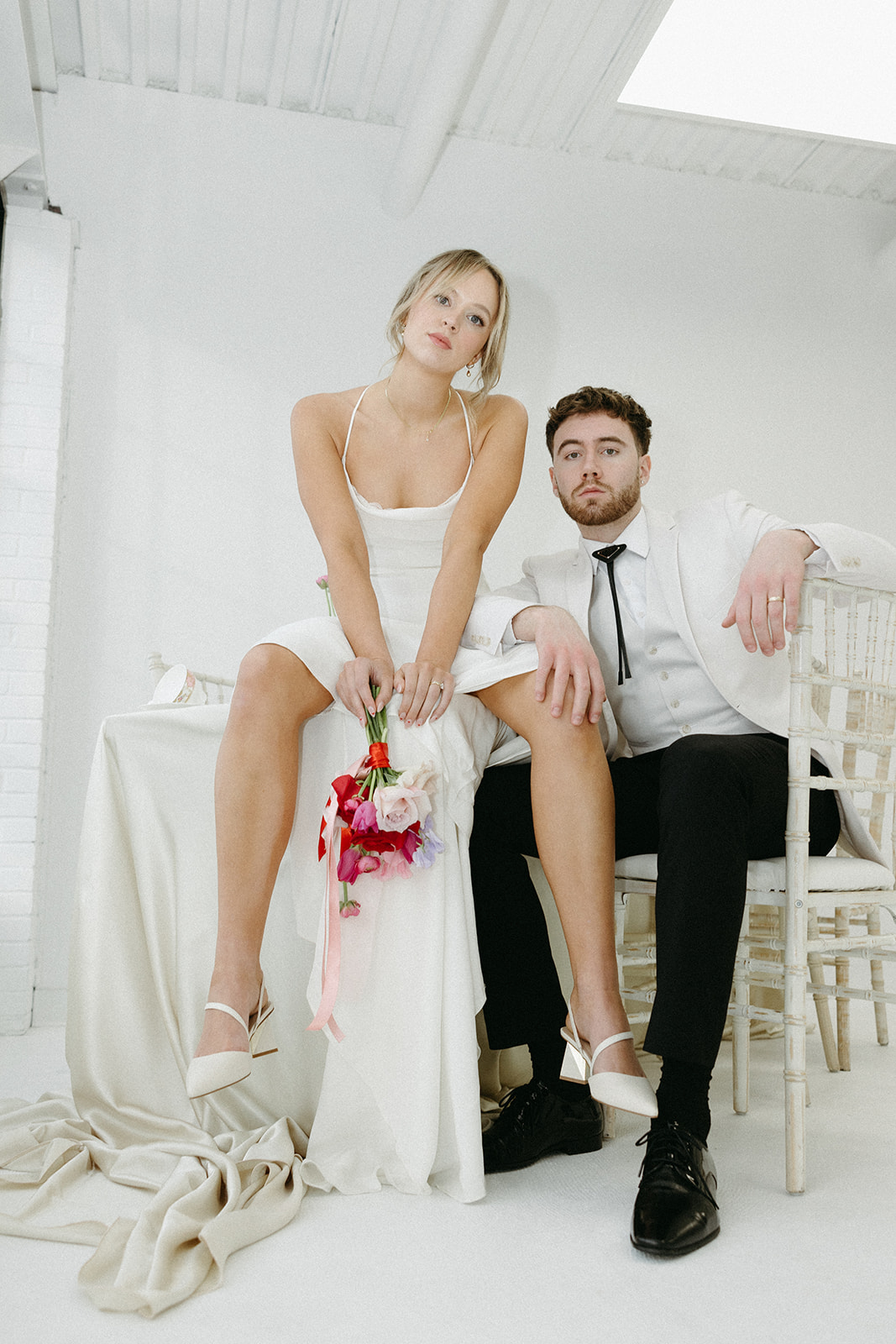 Funky reception setup with vibrant retro-inspired decor and playful design elements like beautiful vintage china, bold coloured candles, and bright pink posy bridal bouquet in a modern meets retro themed editorial shoot.