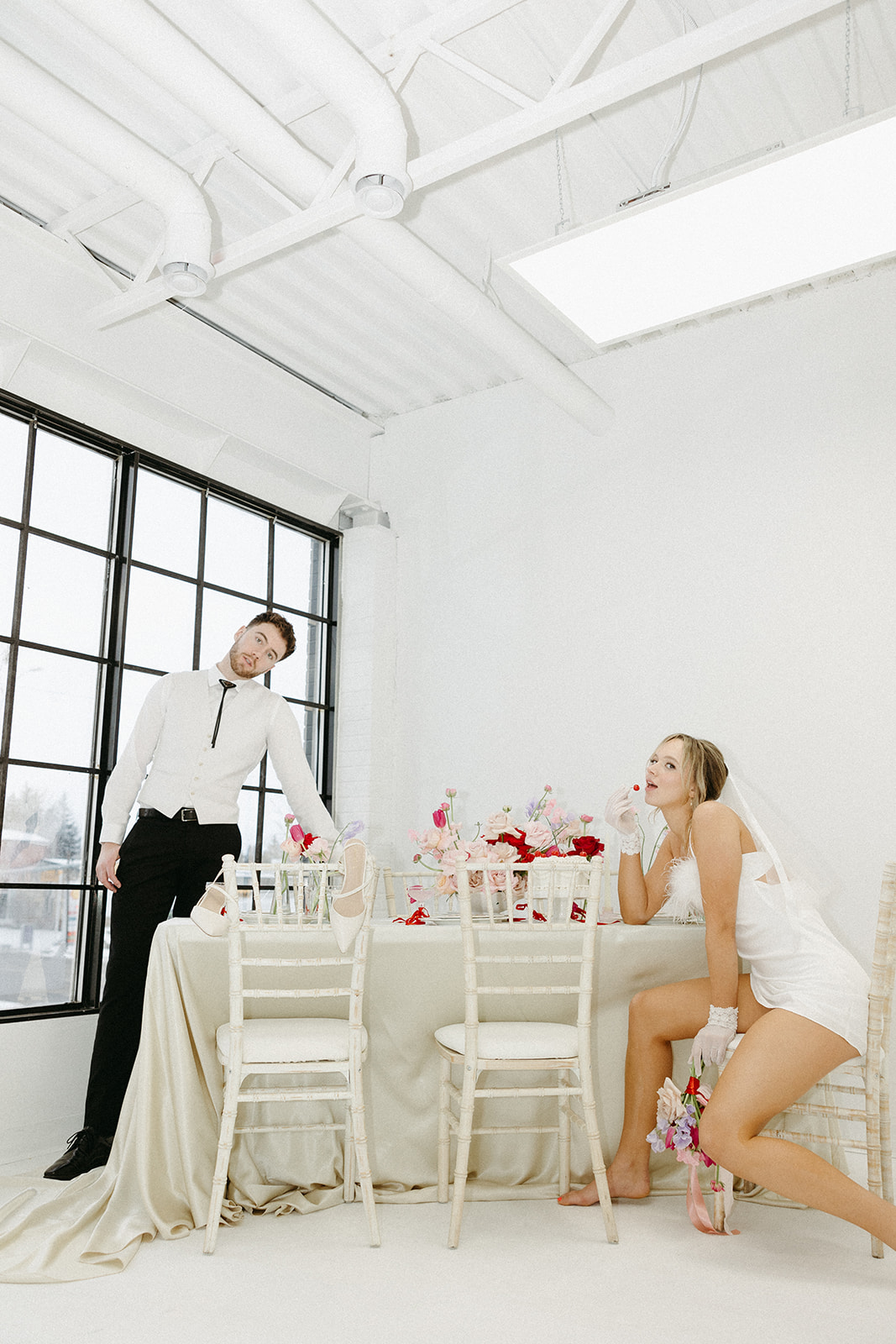 Editorial wedding shoot featuring retro wedding dress and groom’s suit, styled with modern minimalist elements. Funky reception setup with vibrant retro-inspired decor and playful design elements, bold coloured candles, and modern flowers.