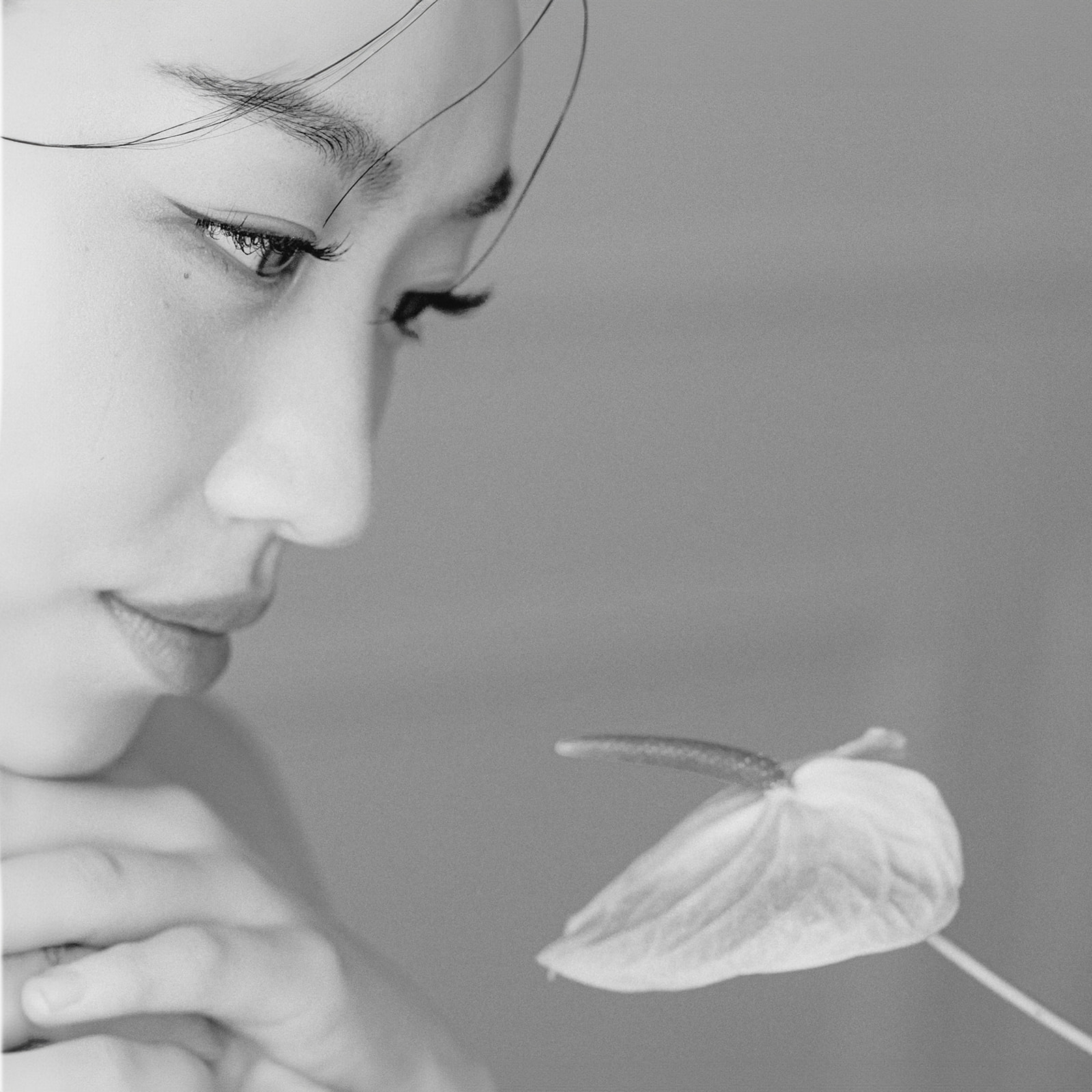 Black and white bridal portrait. Close-up of bride admiring florals.