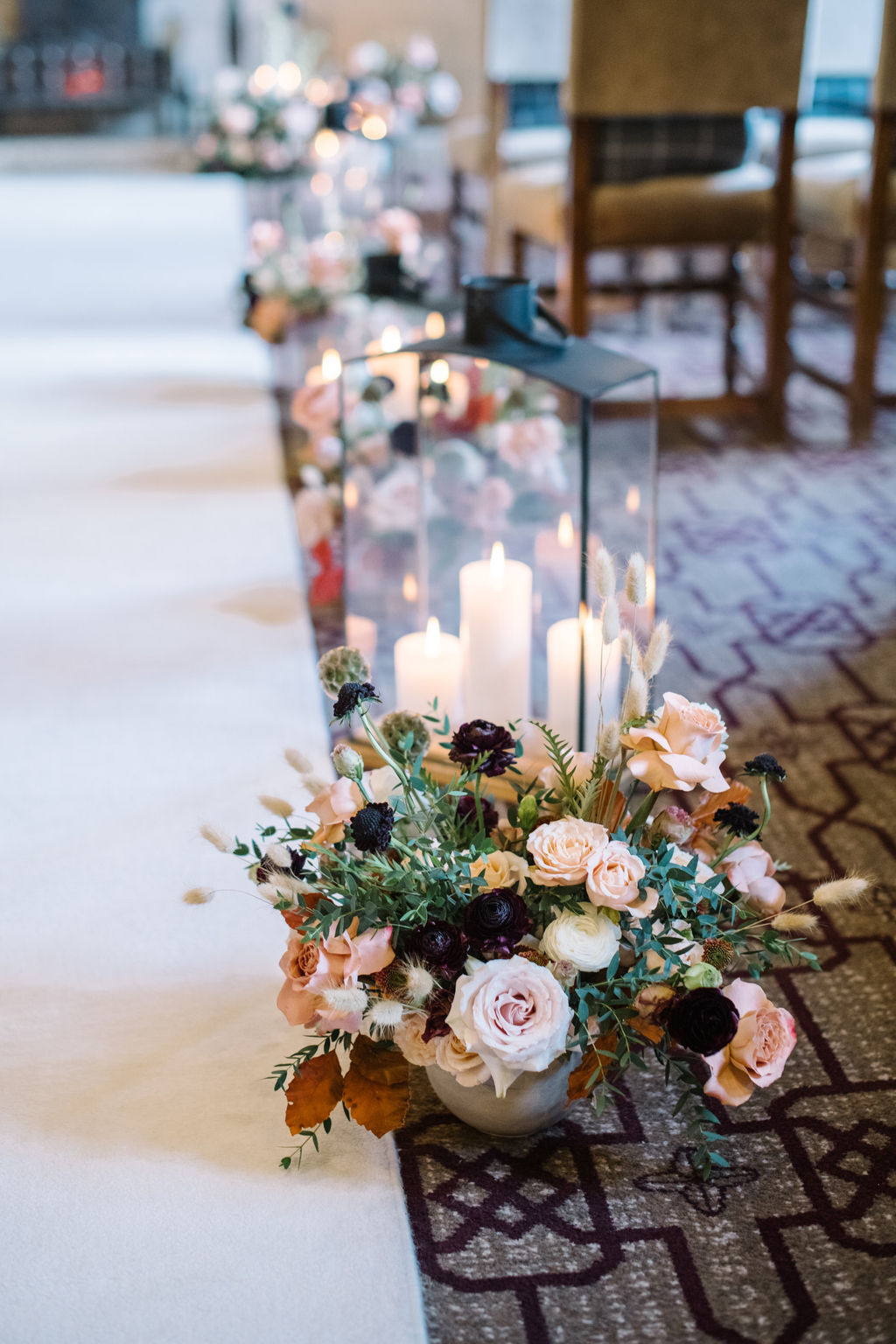 Lanterns, candles and lush winter florals line the aisle, creating a romantic and intimate setting for the cozy wedding ceremony in the Angus Room at Fairmont Banff Springs,