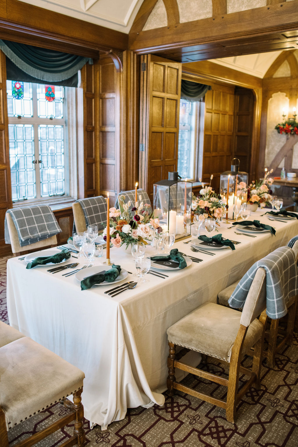 An intimate reception setup in the Angus Room featuring rich florals, candlelight, and a romantic winter ambiance. Wedding table styled with lanterns, candles, florals and blankets.