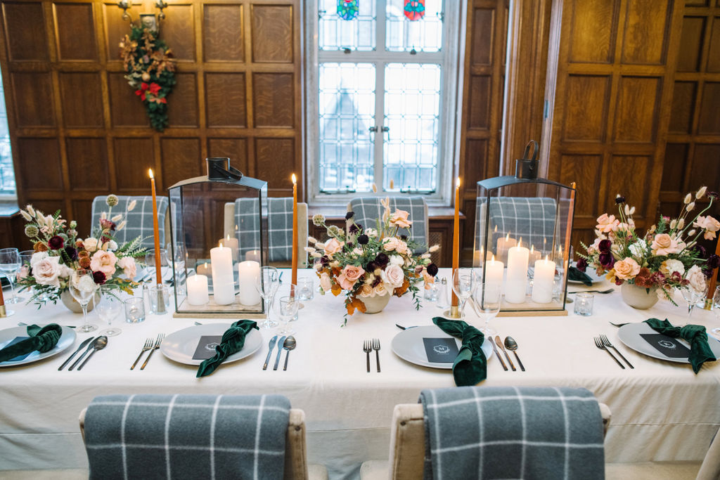 An intimate reception setup in the Angus Room featuring rich florals, candlelight, and a romantic winter ambiance. Wedding table styled with lanterns, candles, florals and blankets.