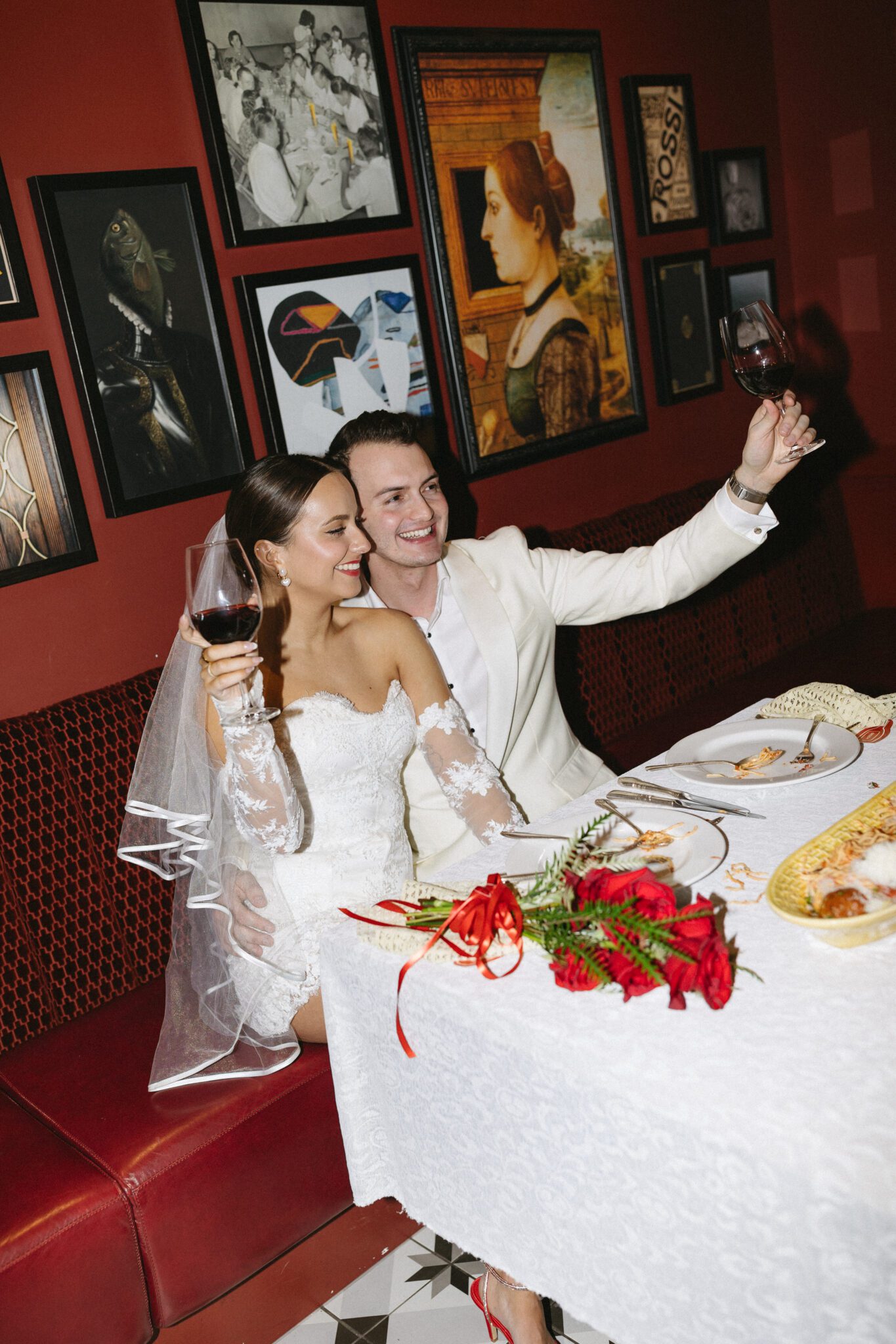 This Italy inspired wedding inspiration at Buffo Restaurant in Calgary, featured on the Brontë Bride Blog, showcases modern sophistication, vintage charm, and a vibrant red colour palette. #brideandgroomattire #lacebridalgown #redrosebouquet #modernweddinginspiration #receptiontoast #restaurantreception