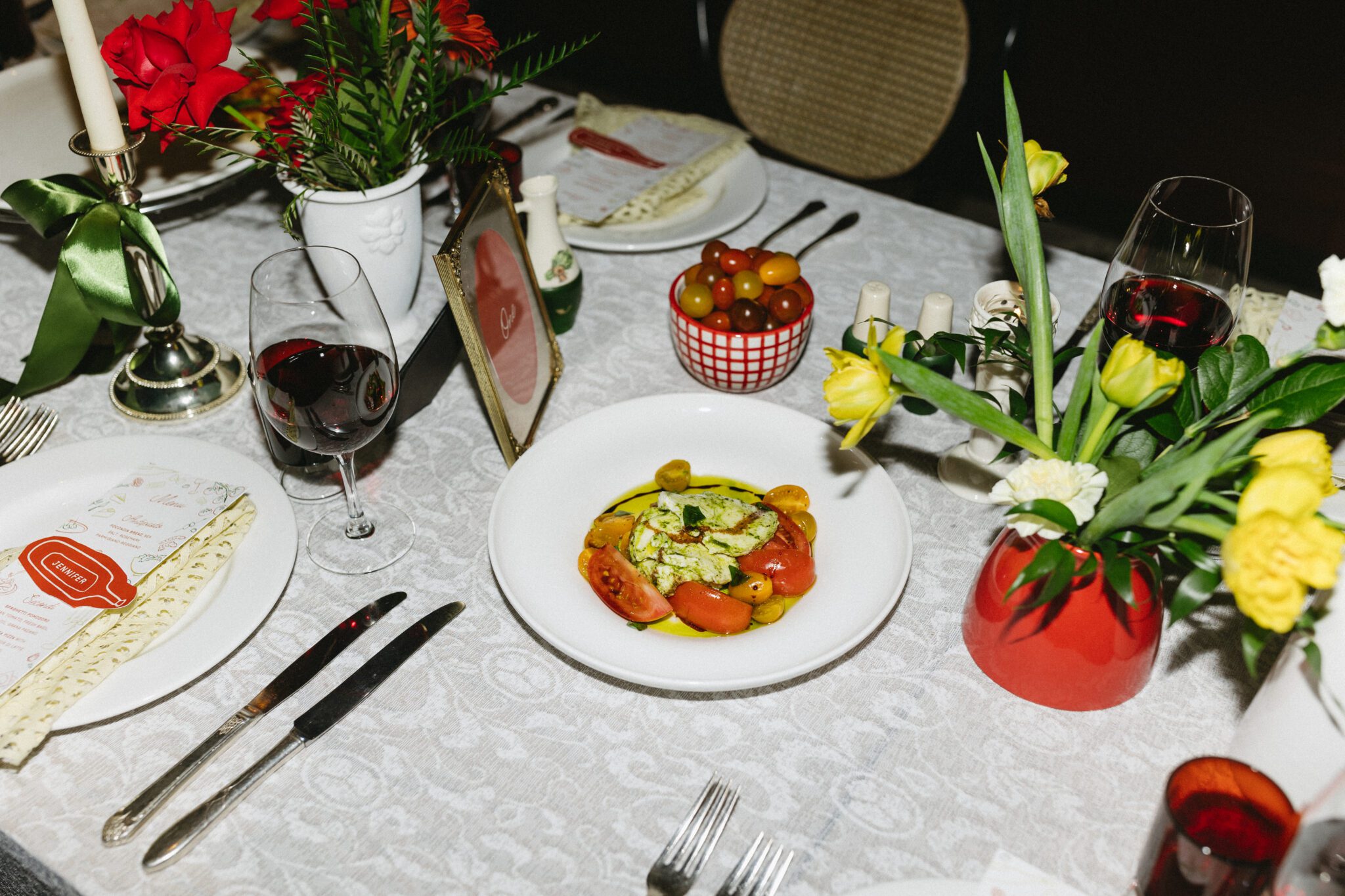 Italy inspired wedding reception table with a colour palette of red, green, yellow and white. Retro meets modern style with european design influence. Tablesettings, menus and placecards, table numbers, floral centerpieces and food. #retroweddinginspiration #restaurantreception #vintageweddinginspo #weddingtable #italyinspiredwedding