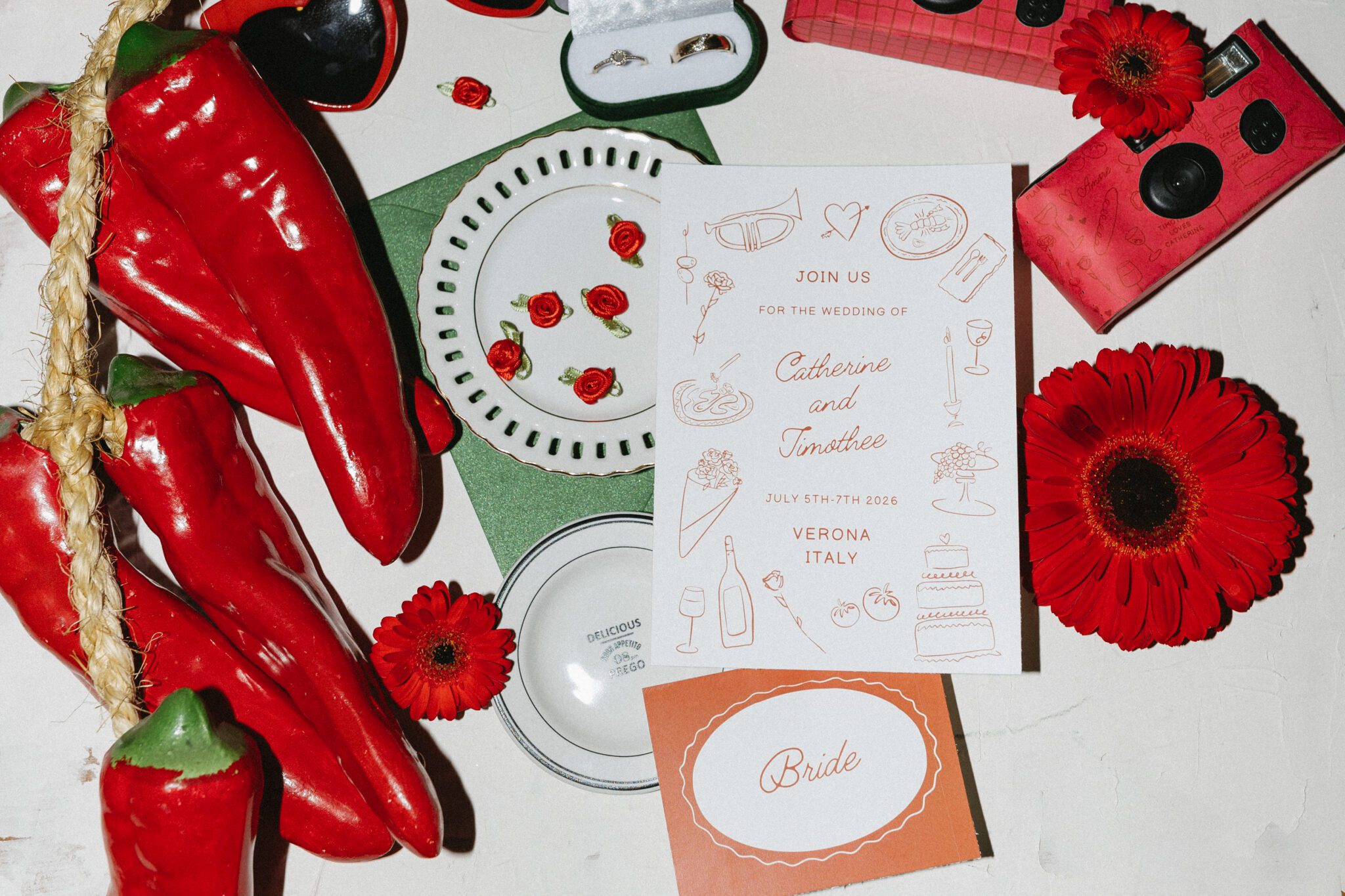 This wedding inspiration at Buffo Calgary, showcases modern sophistication, vintage charm, and a vibrant red colour palette. This photo shows the wedding stationery suite and details in a flash photo flatlay design. #handdrawninvitation #restaurantreception #vintageweddinginspo #redwedding #italywedding