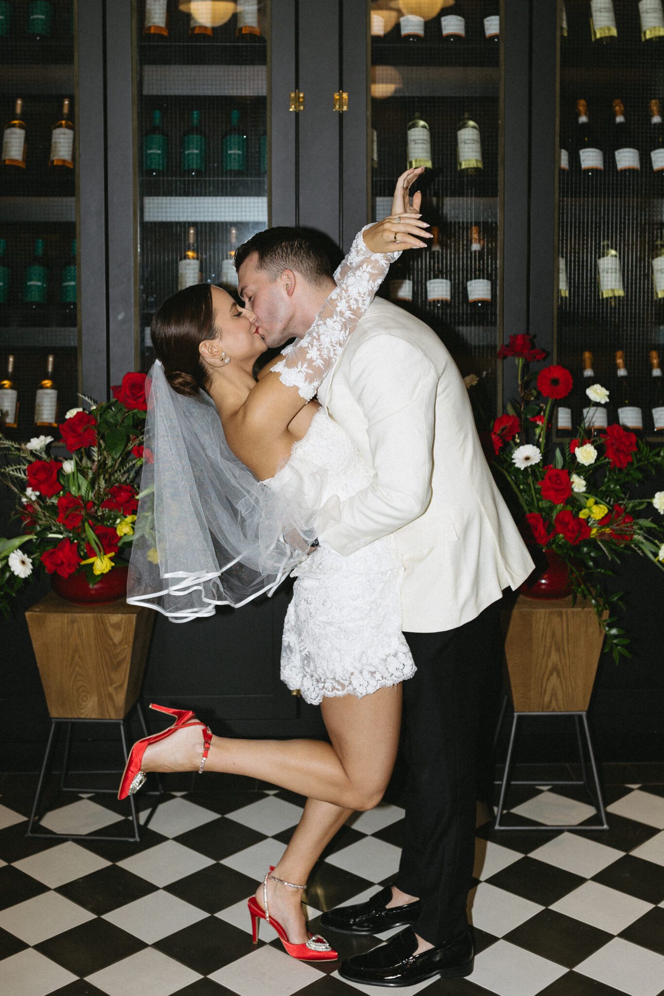 This Italy inspired restaurant wedding inspiration at Buffo Calgary, showcases modern sophistication, vintage charm, retro details, and a vibrant red colour palette. #brideandgroomattire #shortbridaldress #modernretroceremony #modernweddinginspiration #firstkiss #ceremonykiss