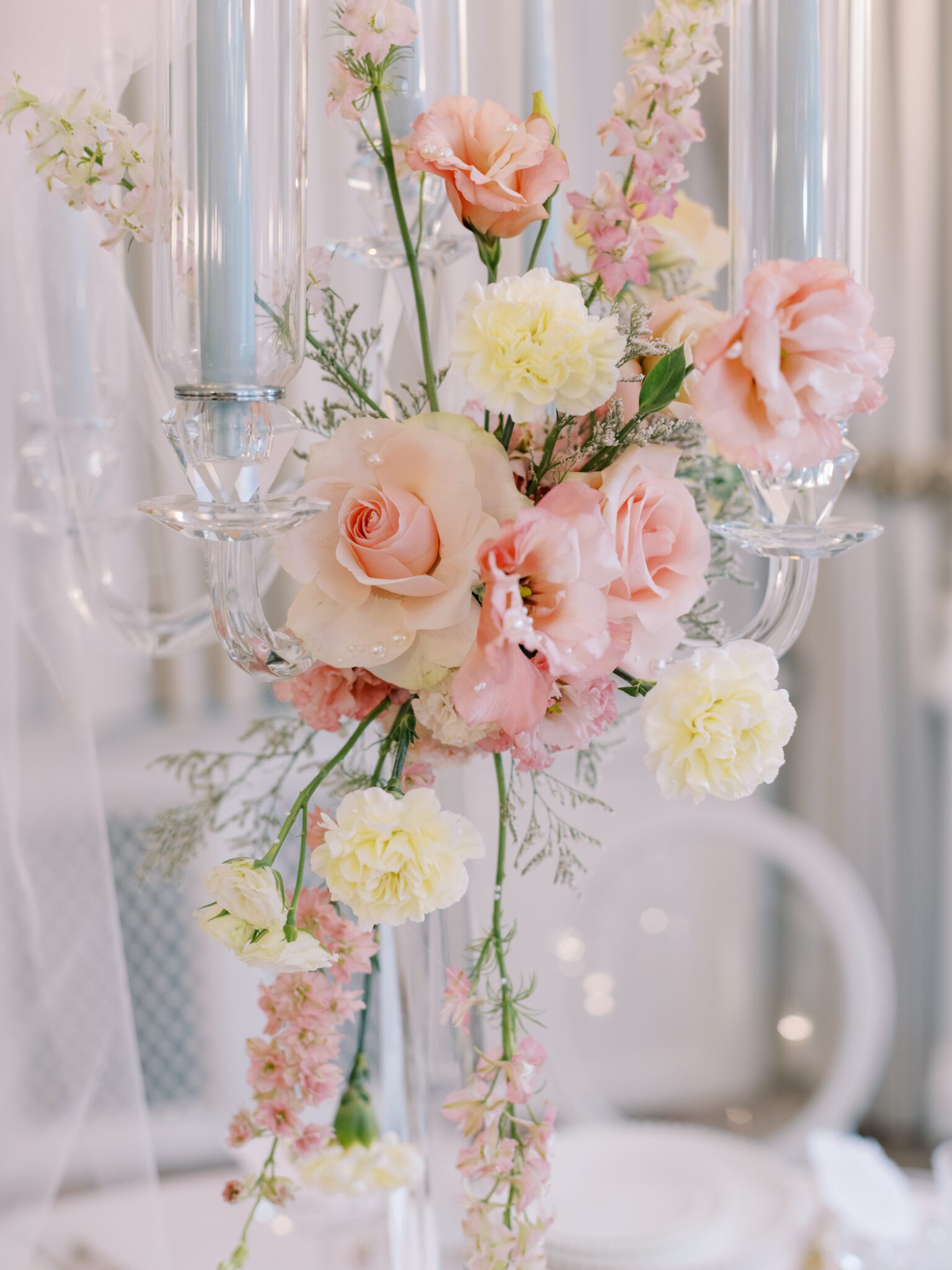 Round blush pink wedding table with crystal candelabra and pale blue candles. Floral centerpiece with Blush roses and pale yellow carnations.