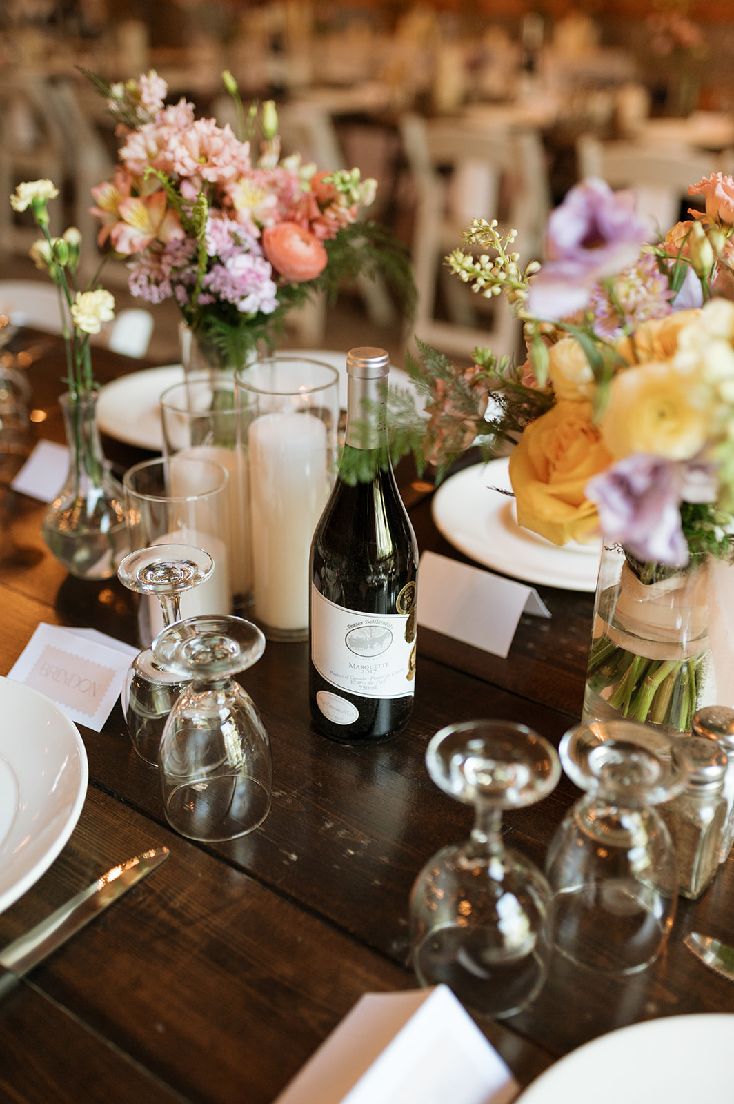 Rustic Summer wedding in Kootenay BC, Barn wedding reception tables at Hillside Lodge & Chalets in Golden BC - wood farmhouse table with colourful wildflowers and pillar candles