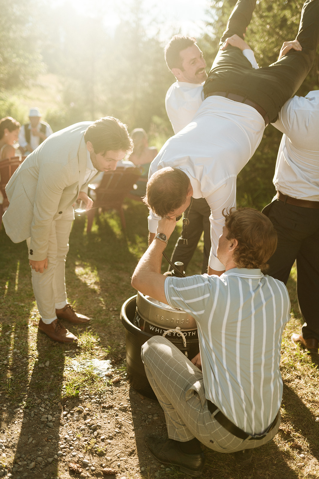 Kootenay Summer Wedding in Golden BC, Cocktail Hour Inspiration - Groom doing a keg stand at cocktail hour